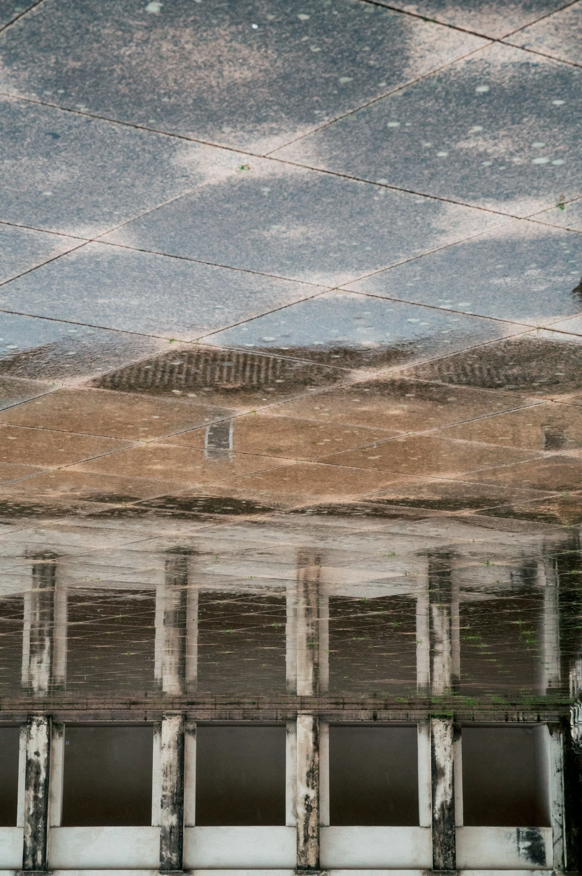 Flooded outdoor area with reflections of a building and tables in water