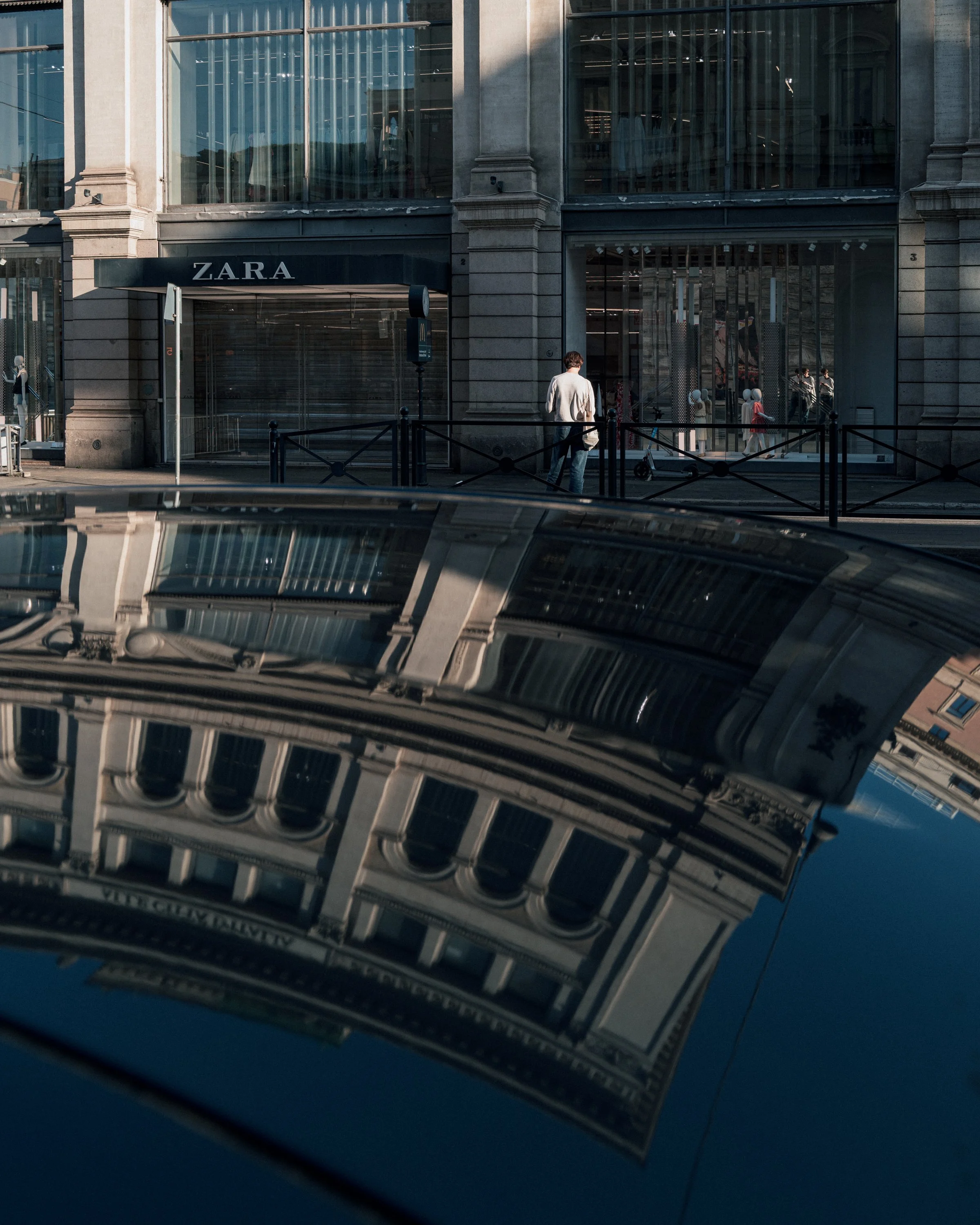 Reflection of a historic building with ornate details in a parked car's reflective surface.