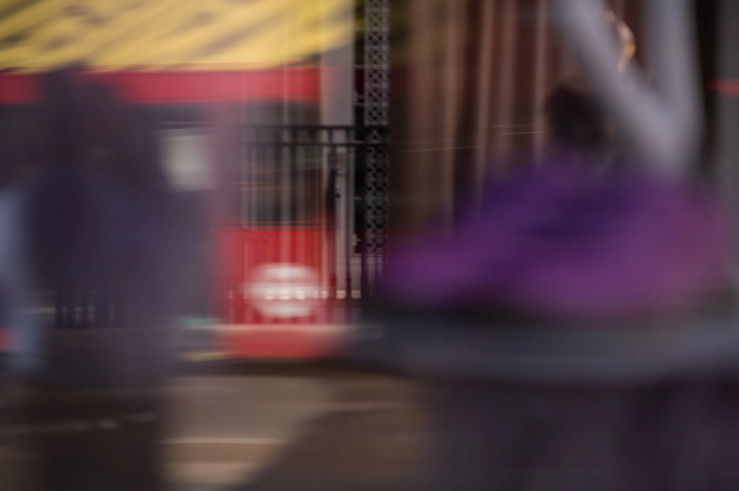 Blurred image of a grocery store aisle with shelves and products, including a red item and purple flowers.