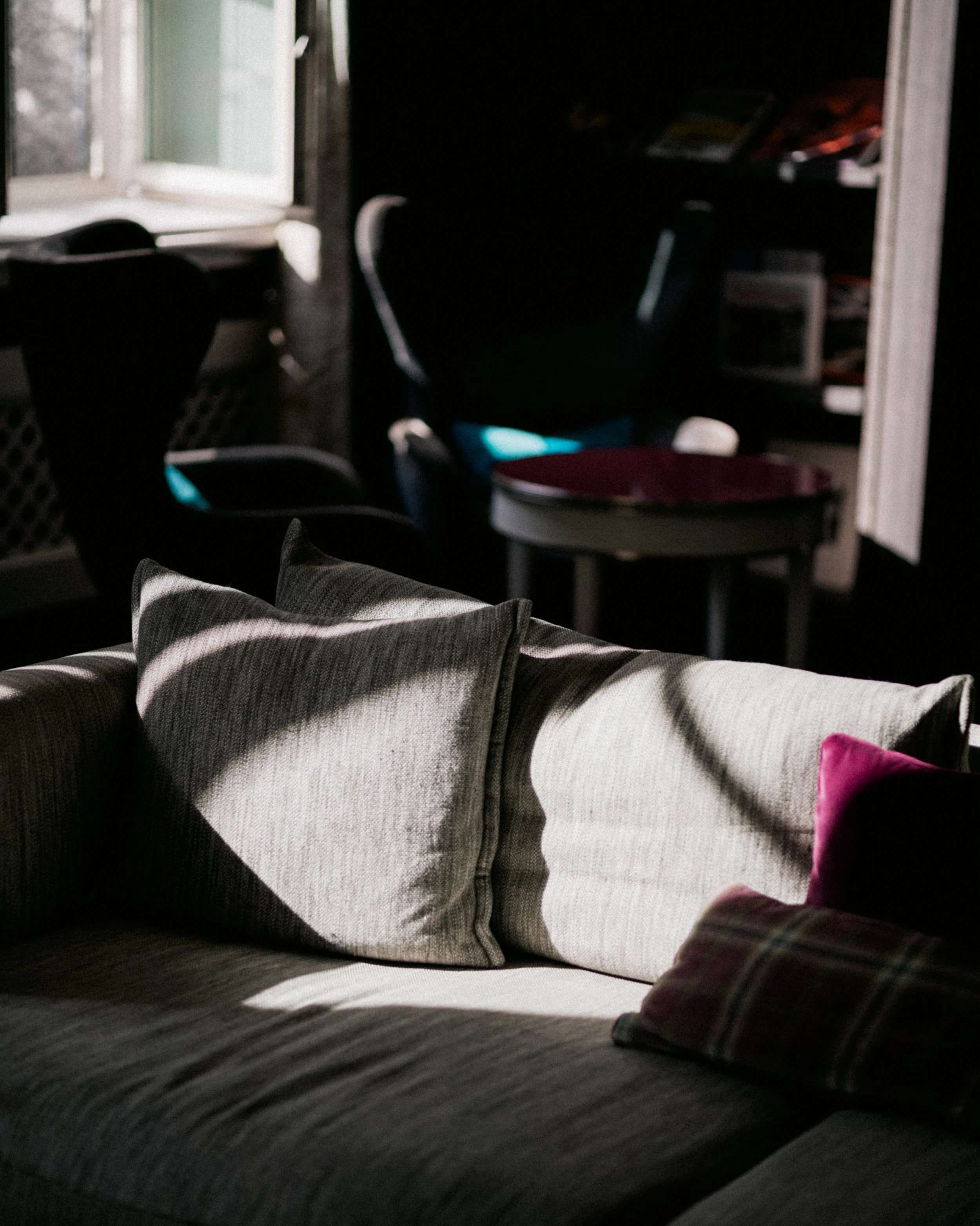 A cozy living room with a couch, pillows, and a window letting in natural light.