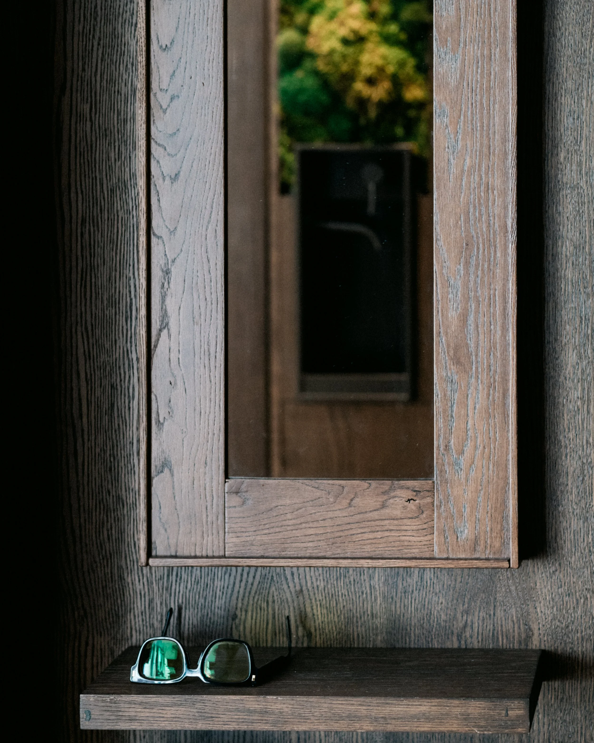 Pair of sunglasses placed on a wooden shelf.
