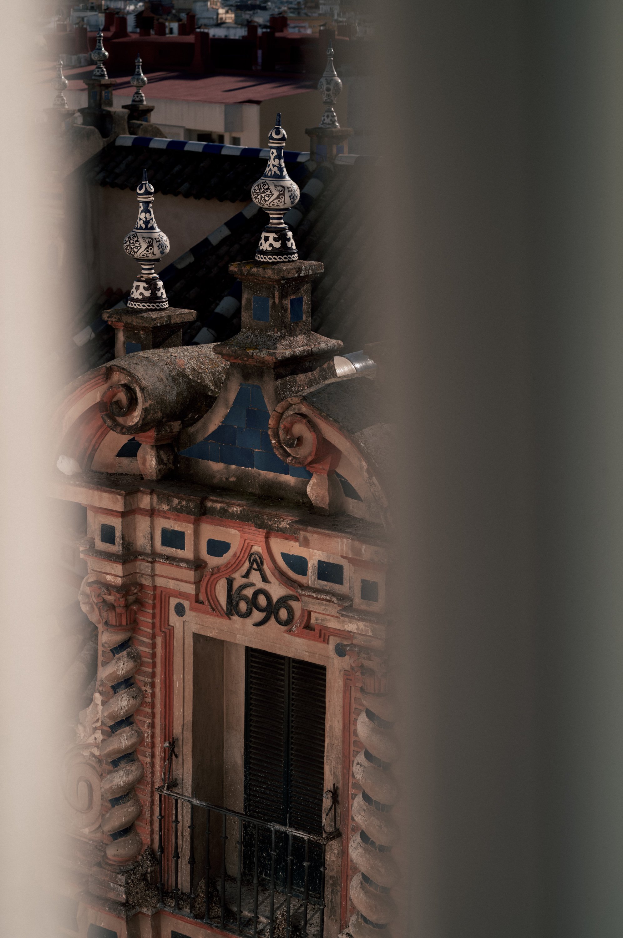 Close-up view of an ornate building facade with decorative elements and a date inscribed as 1696, partially obscured by window frames.