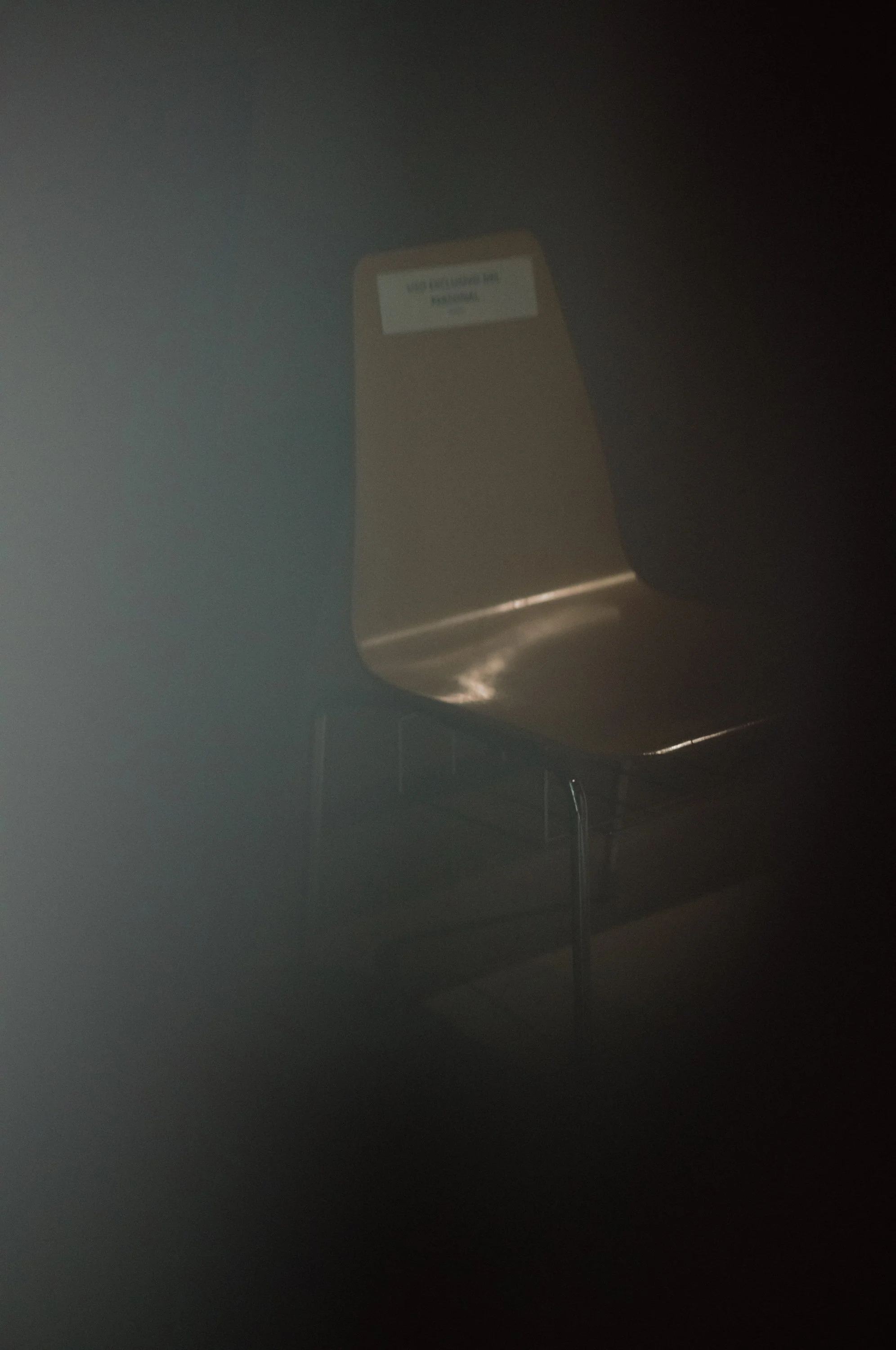 A reflective gold-colored chair in a dimly lit room with a dark background.