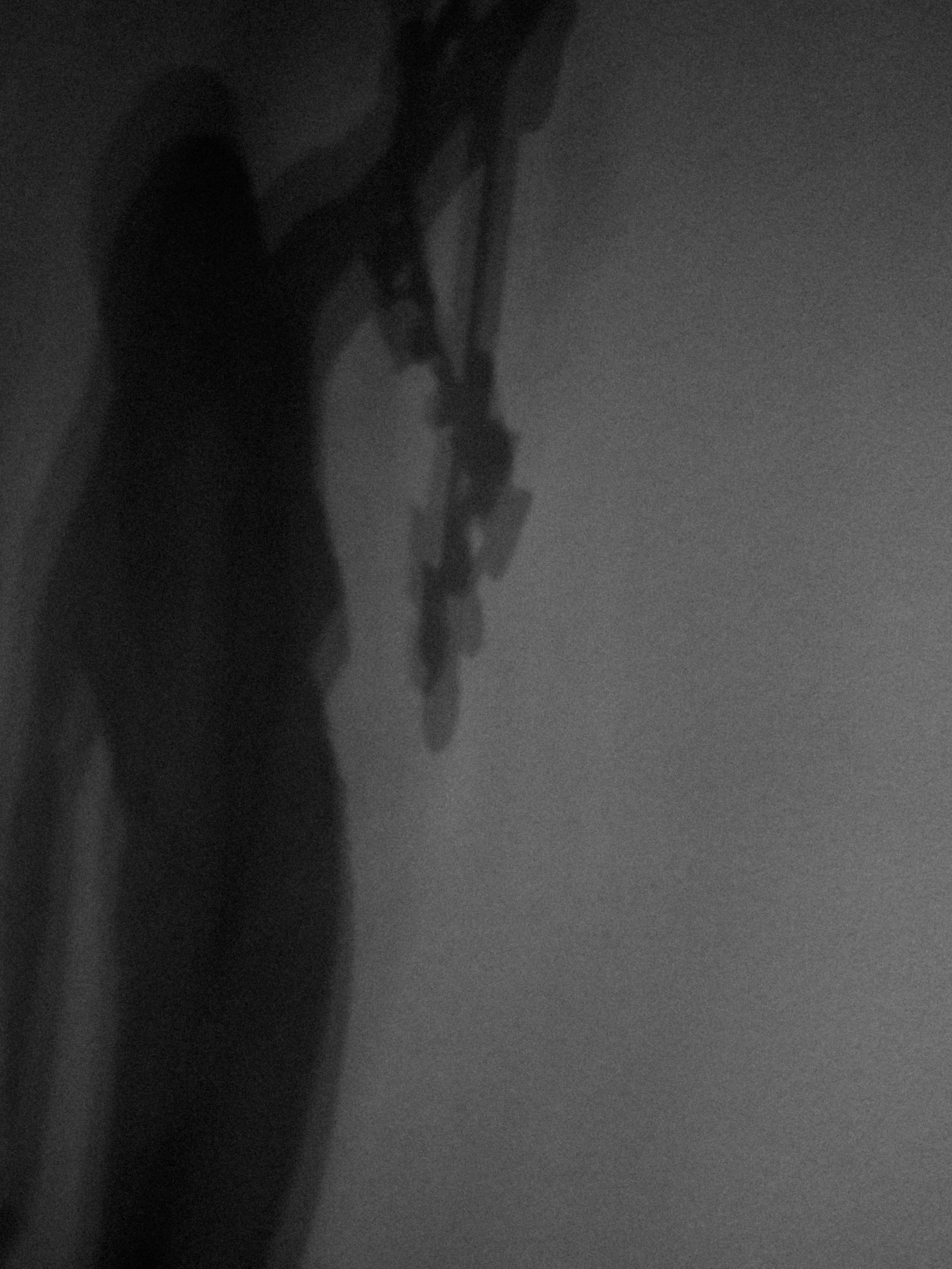 Black and white close-up photo of a person's face with glasses, with shadowed lighting.