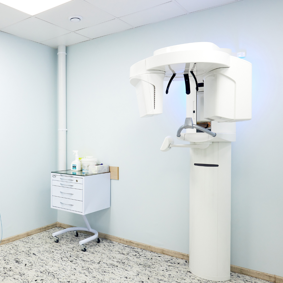 Salle de radiologie avec un appareil de radiographie et un chariot de médicaments ou matériel médical.