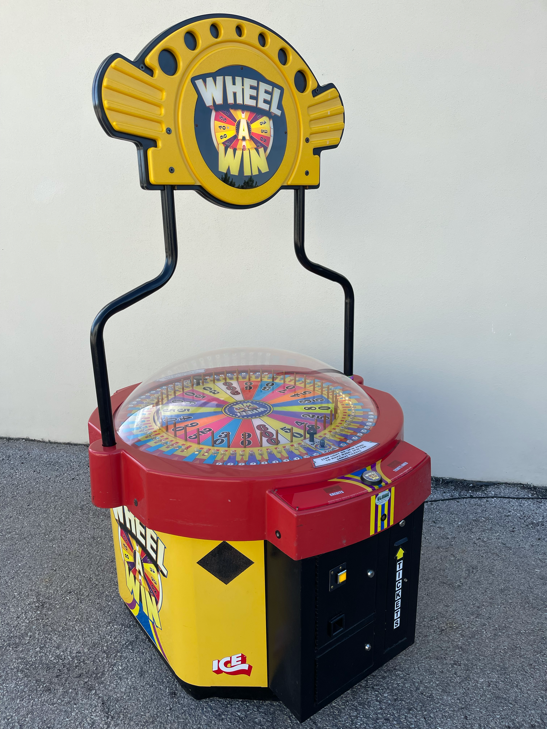 Máquina de roda gigante inflável do jogo Wheel Win na cor vermelha, com um letreiro amarelo com detalhes pretos e em formato de roda dianteiro, exibindo o logo da marca ICE.