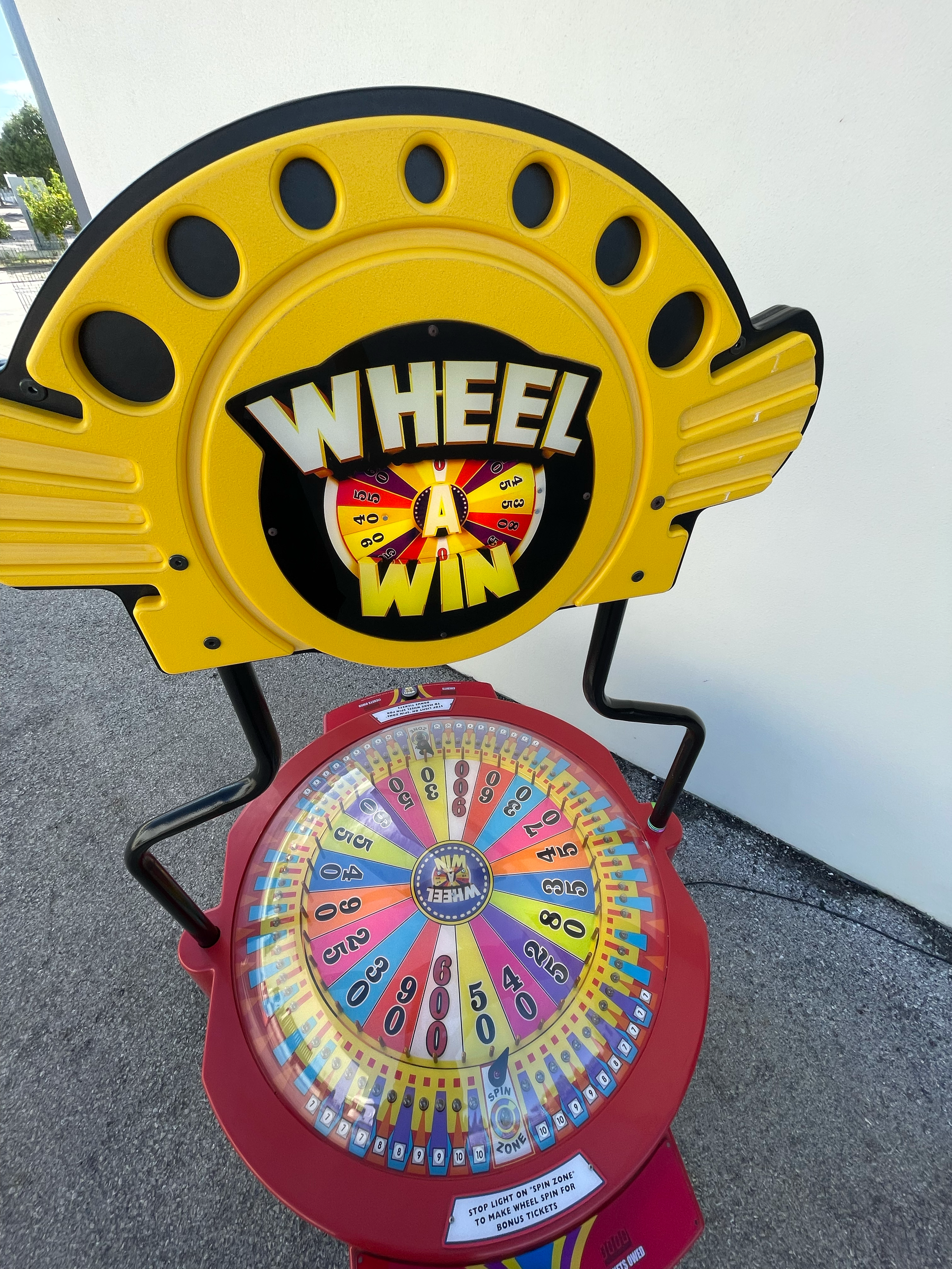 Imagem de uma roleta de um Jogo de Mão (Wheel of Fortune) com cores vibrantes e uma placa na parte superior escrita 'Wheel of Fortune'.
