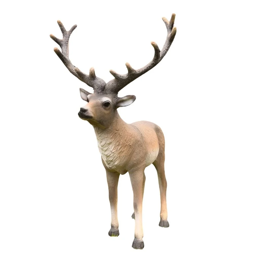 Três esculturas de cervos com chifres grandes em um jardim com grama, árvores e muro verde ao fundo.