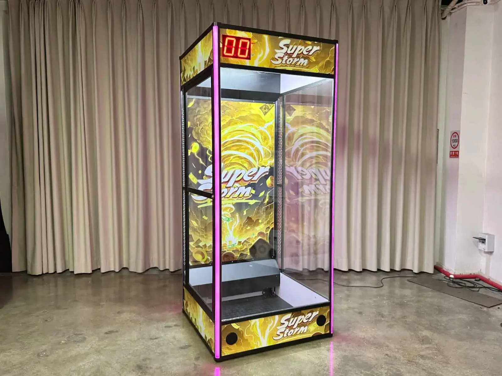 máquina de jogos de arcade de panfletagem com decoração amarelo e preto, marcador digital na parte superior, cercada por cortinas brancas em um ambiente interno
