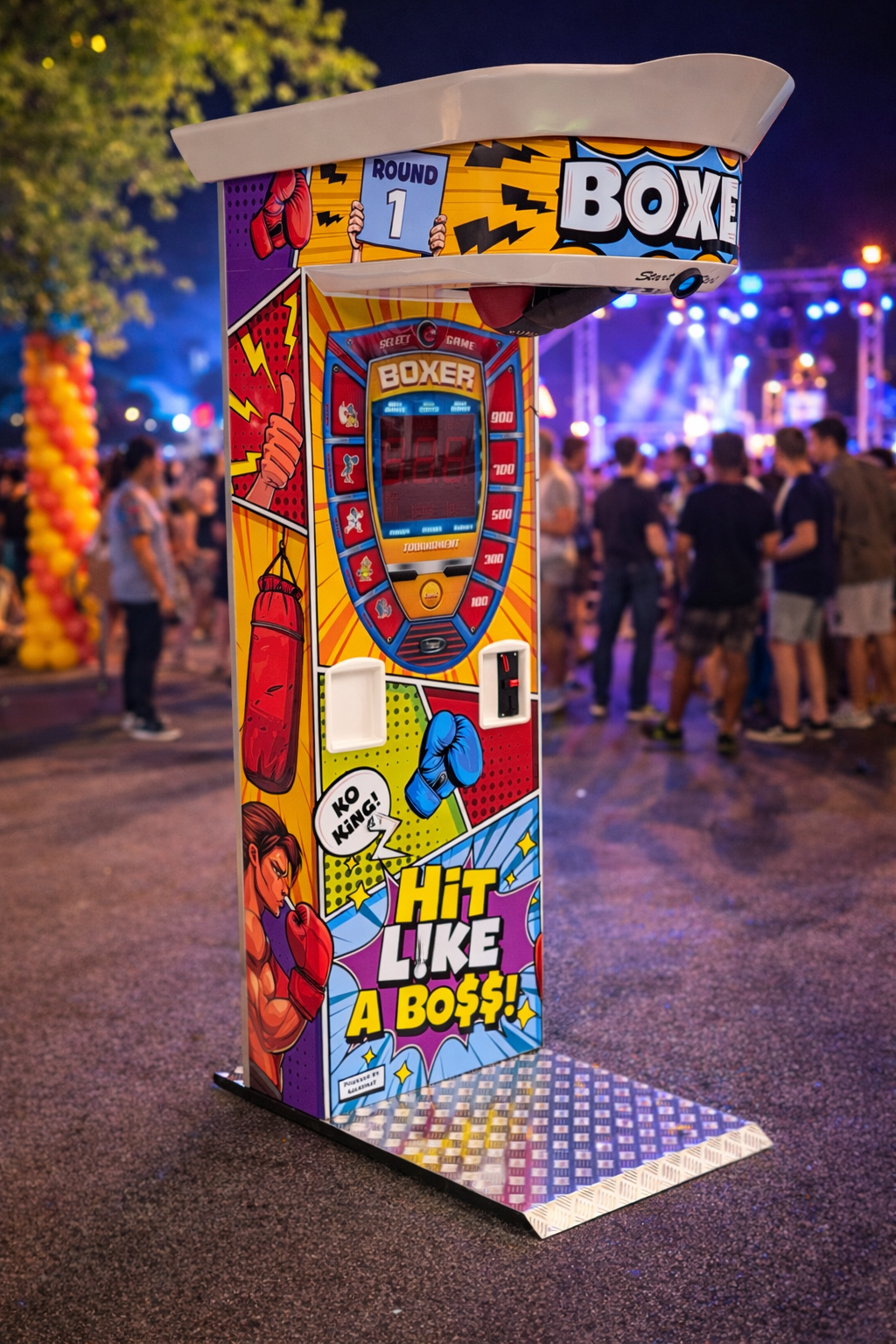 Máquina de basquete com tema de boxe, decorada com desenhos de uma luva de boxe, saco de pancadas e uma mulher lutadora, em uma festa ao ar livre à noite com pessoas ao fundo, luzes coloridas e palco.