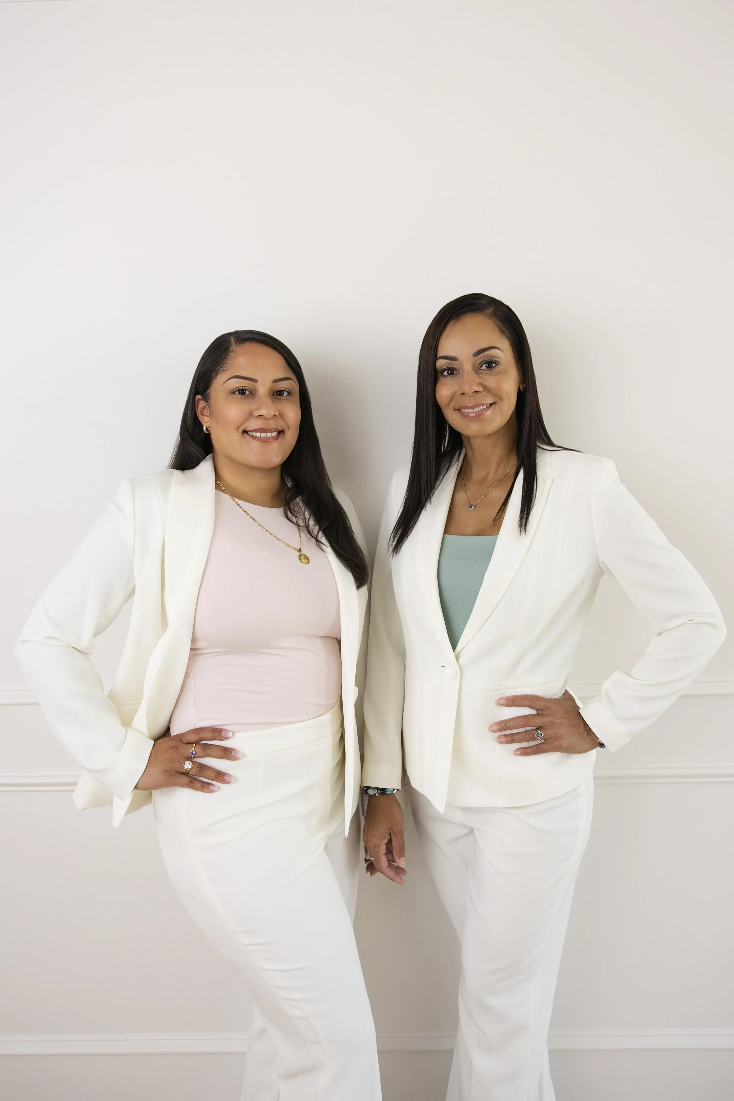 Two women in cream suits and pink or green shirts smiling capturing beauty and essence in timeless, artful images by Storm Pierre Photography in Jacksonville, Richlands, Hampstead, and Sneads Ferry North Carolina
