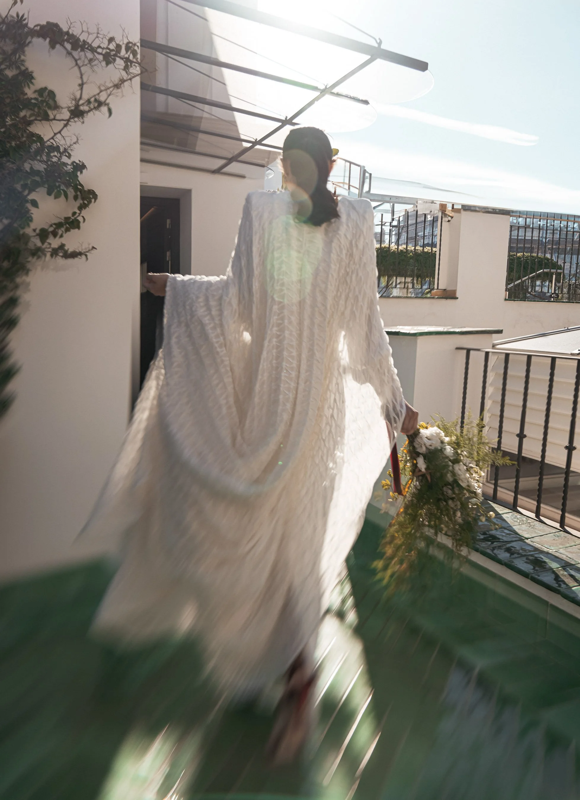 Novia caminando por el balcón con su ramo durante la mañana de su boda