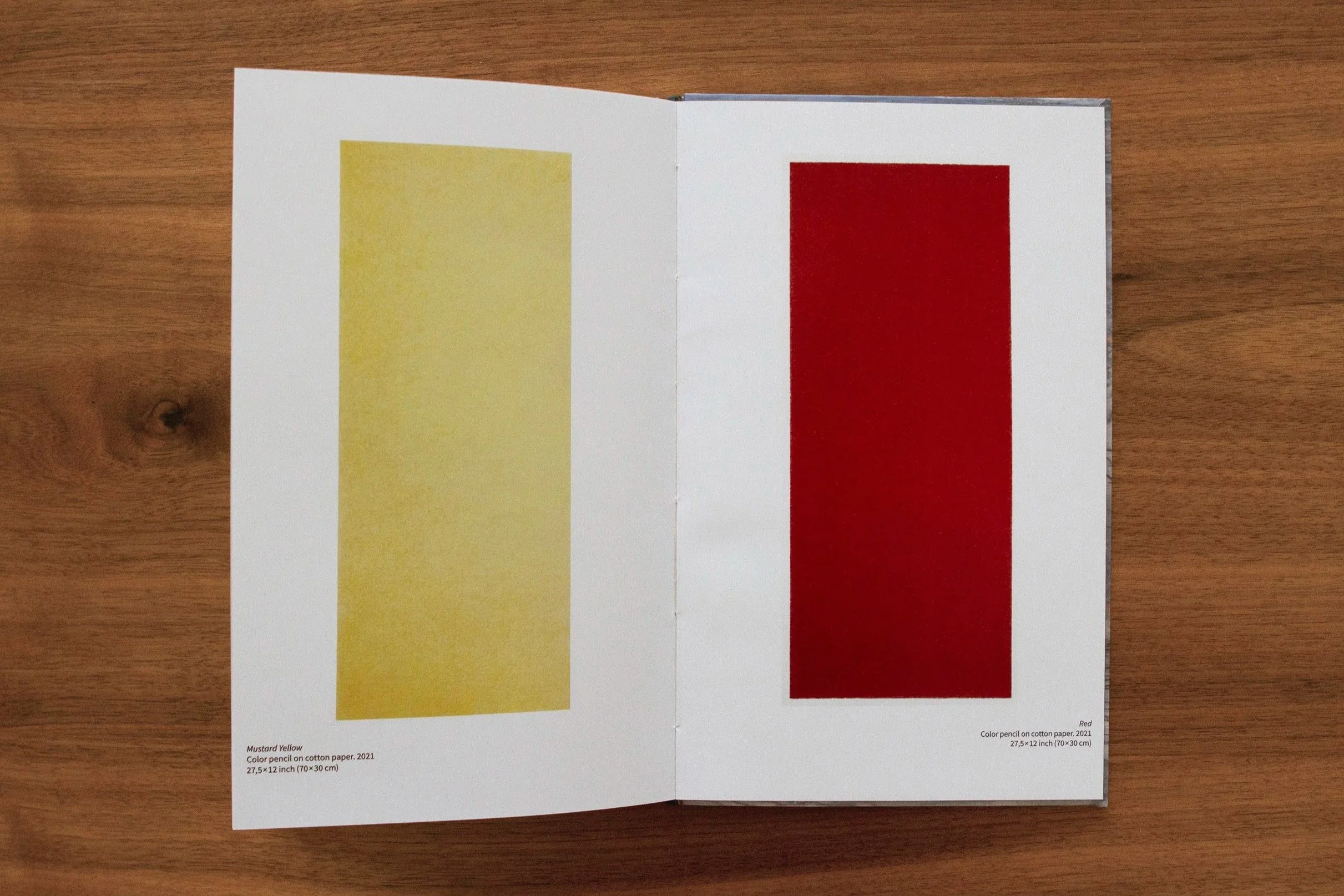 A color printout showing two color swatches: mustard yellow on the left and red on the right, with labels and measurements below each, placed on a wooden surface.