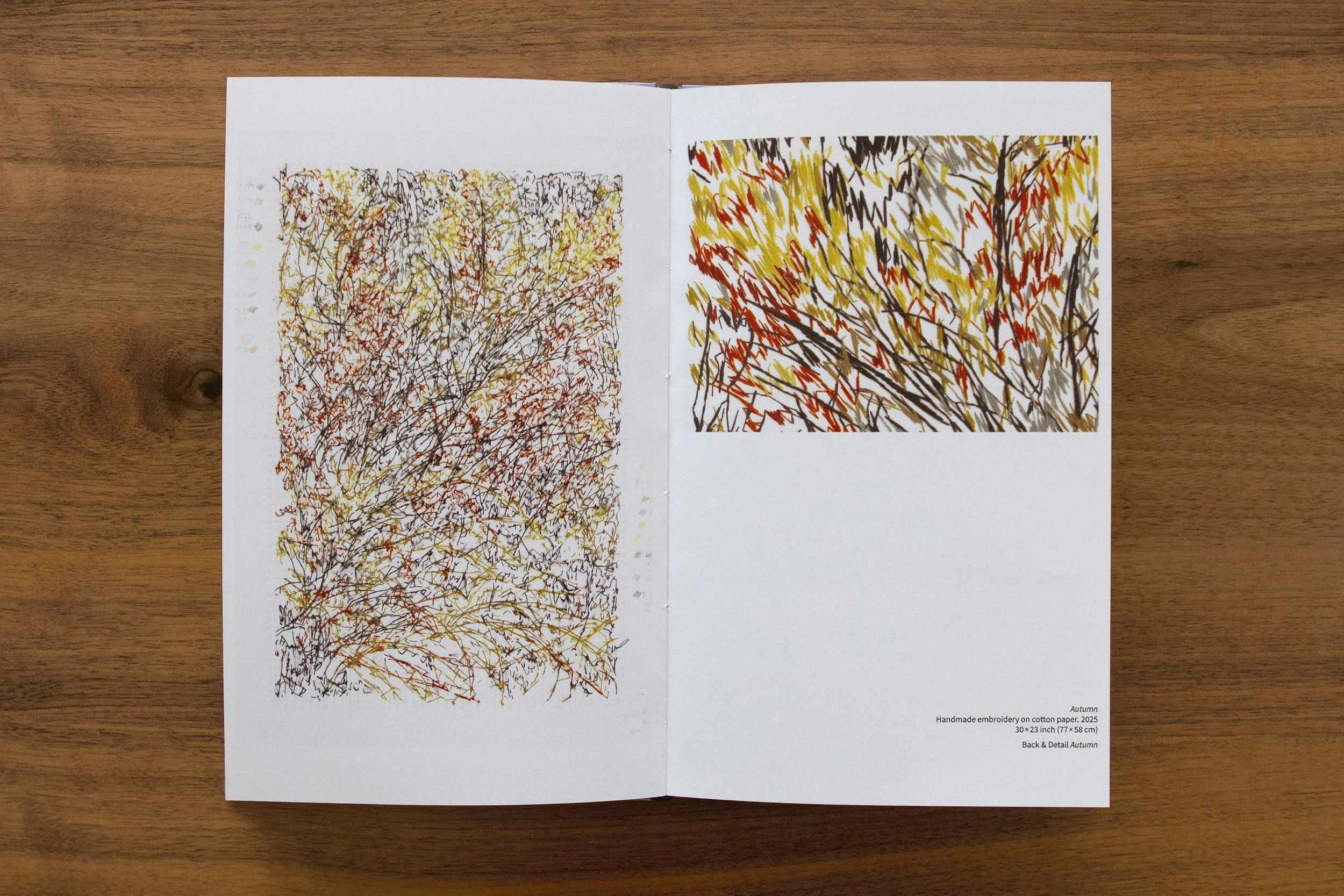 Open sketchbook displaying embroidered autumn scene with abstract tree branches in fall colors; notes in bottom right corner mention handmade embroidery on cotton paper, dimensions, and autumn theme. CATALOG WINTER FLOWERS / artista Maria Valenzuela