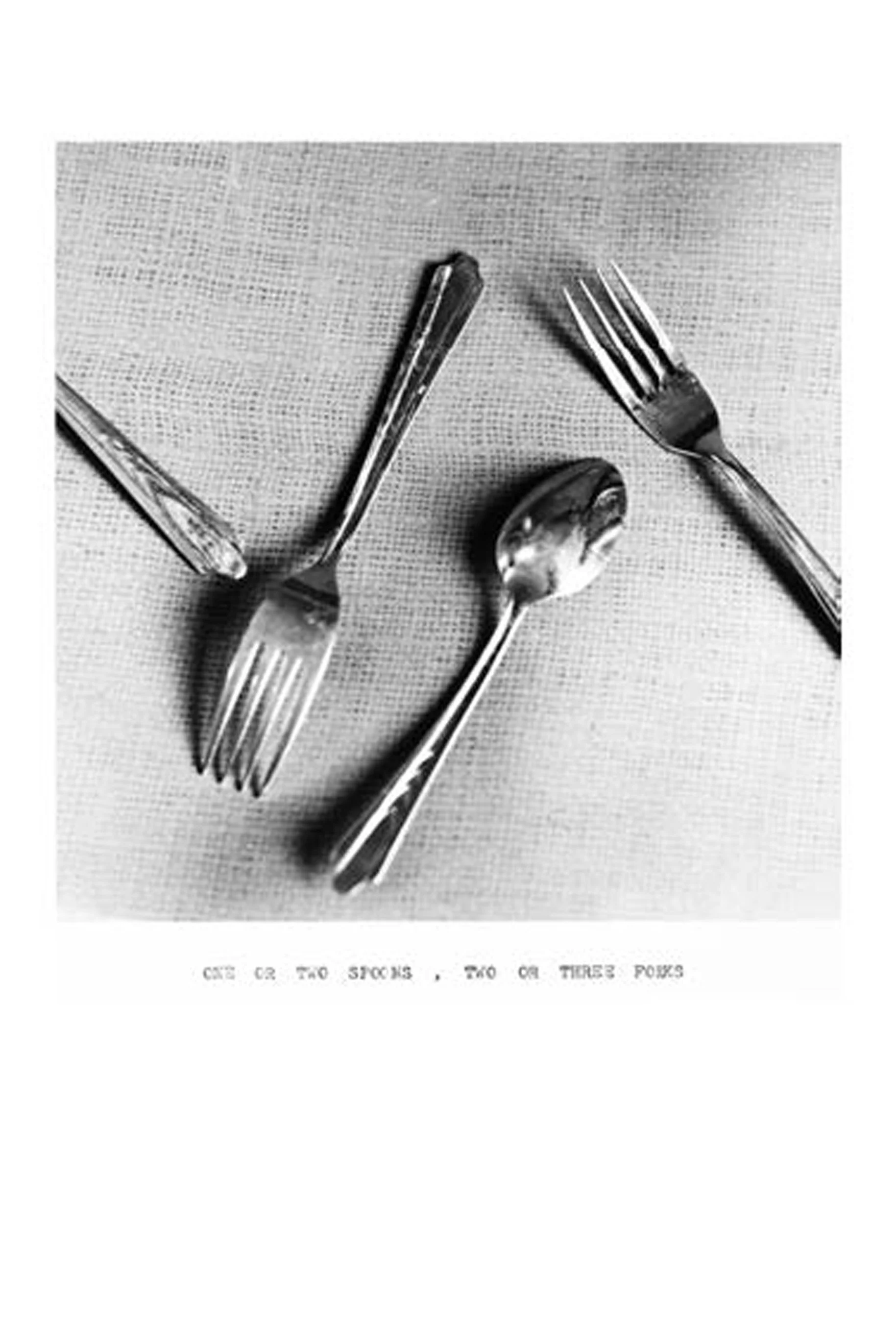 Black and white photo of three forks and a spoon arranged on a textured surface.
