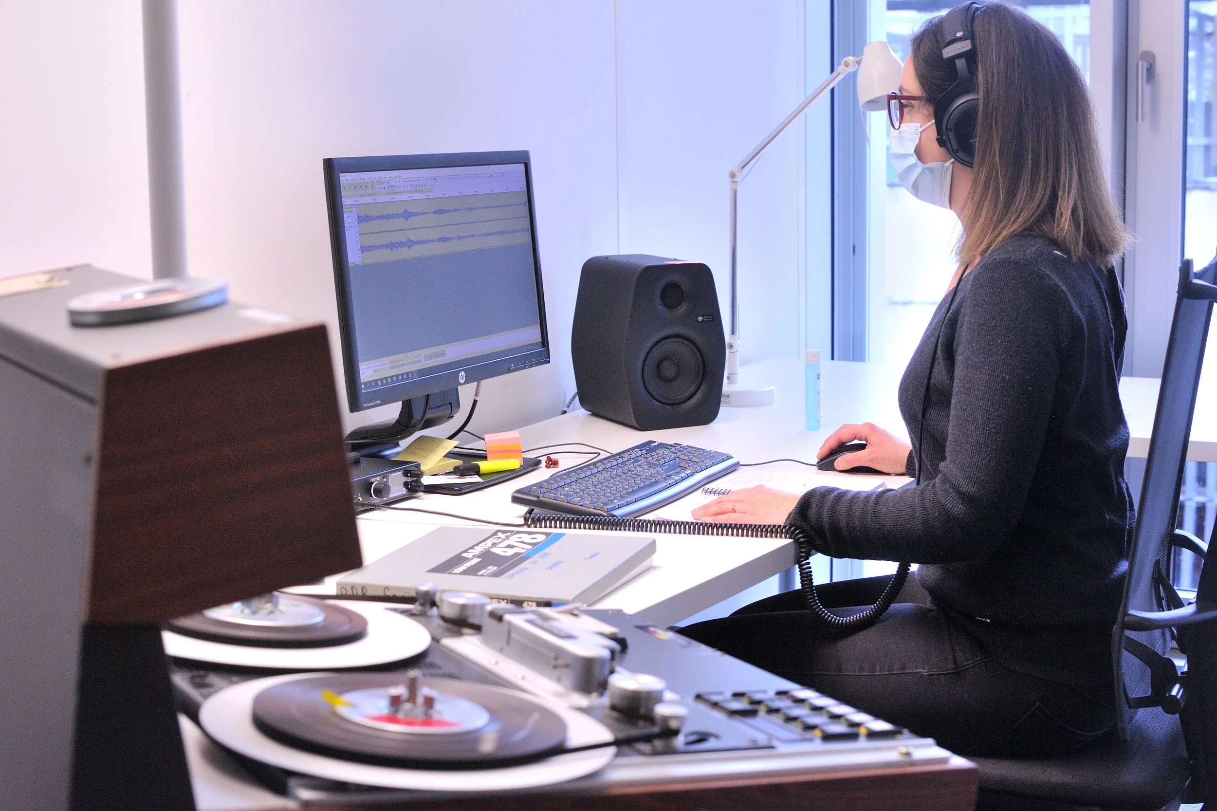 Beim Digitalisieren ist aktives Hören gefragt: Die Tonqualität wird überprüft und gleichzeitig wird der Inhalt in Datenbanken beschrieben. Mitarbeiterin von Radio Fribourg/Freiburg bei der Arbeit. Dezember 2020.