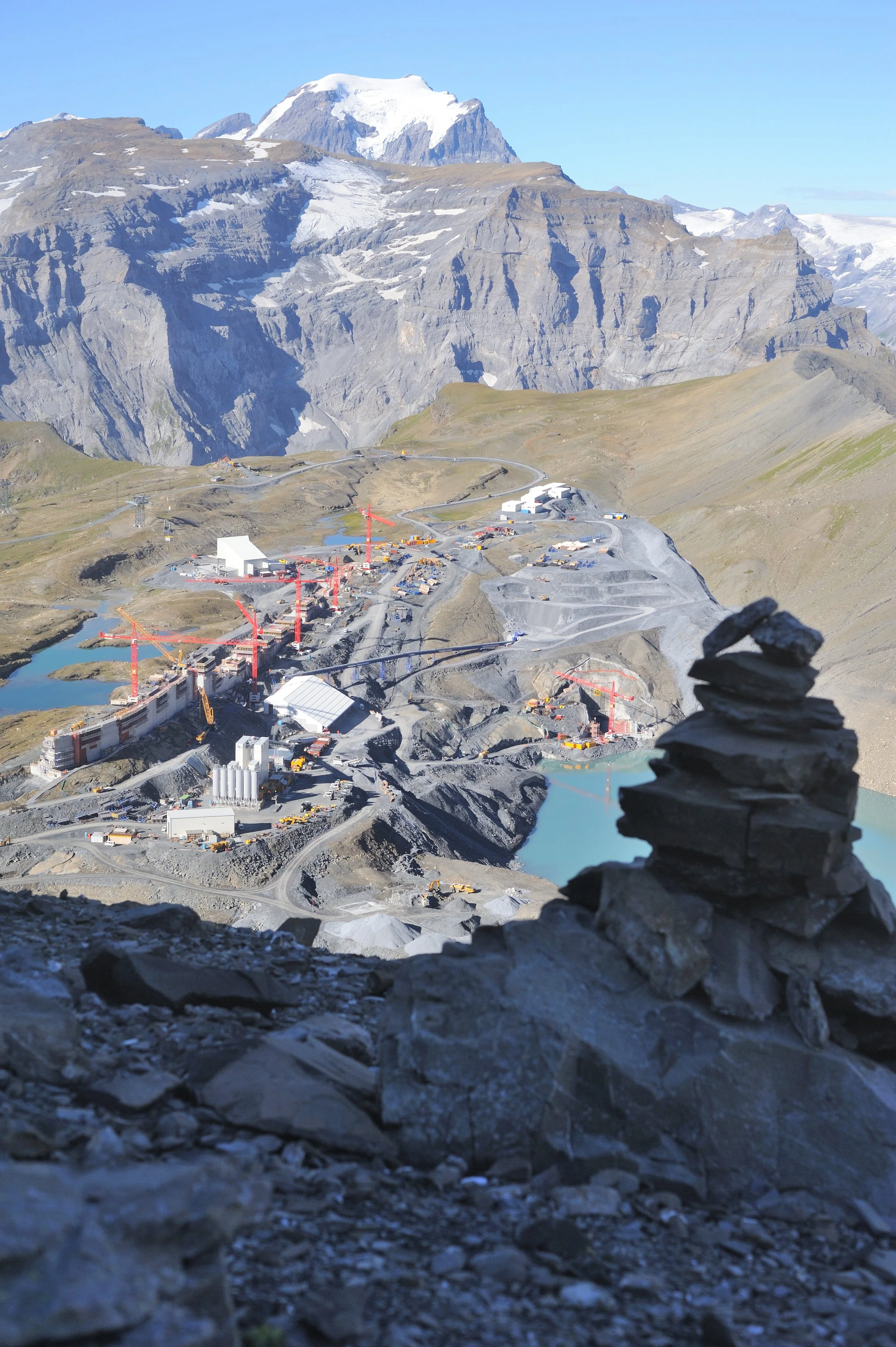 Blick von einem Vorgipfel des Ruchi auf die Baustelle beim Muttsee; rechts der Bildmitte ist der Abfluss in die Pumpspeicherkaverne im Berginneren erkennbar; am Horizont der Tödi