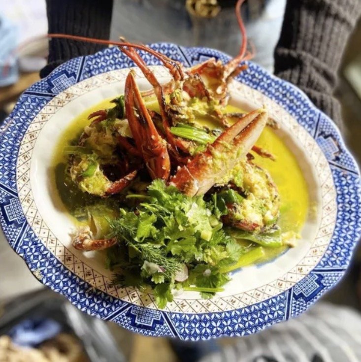 The Rocket Store, one of the Best Restaurants in North Cornwall. Cooked lobster dish with herbs on a blue patterned plate.