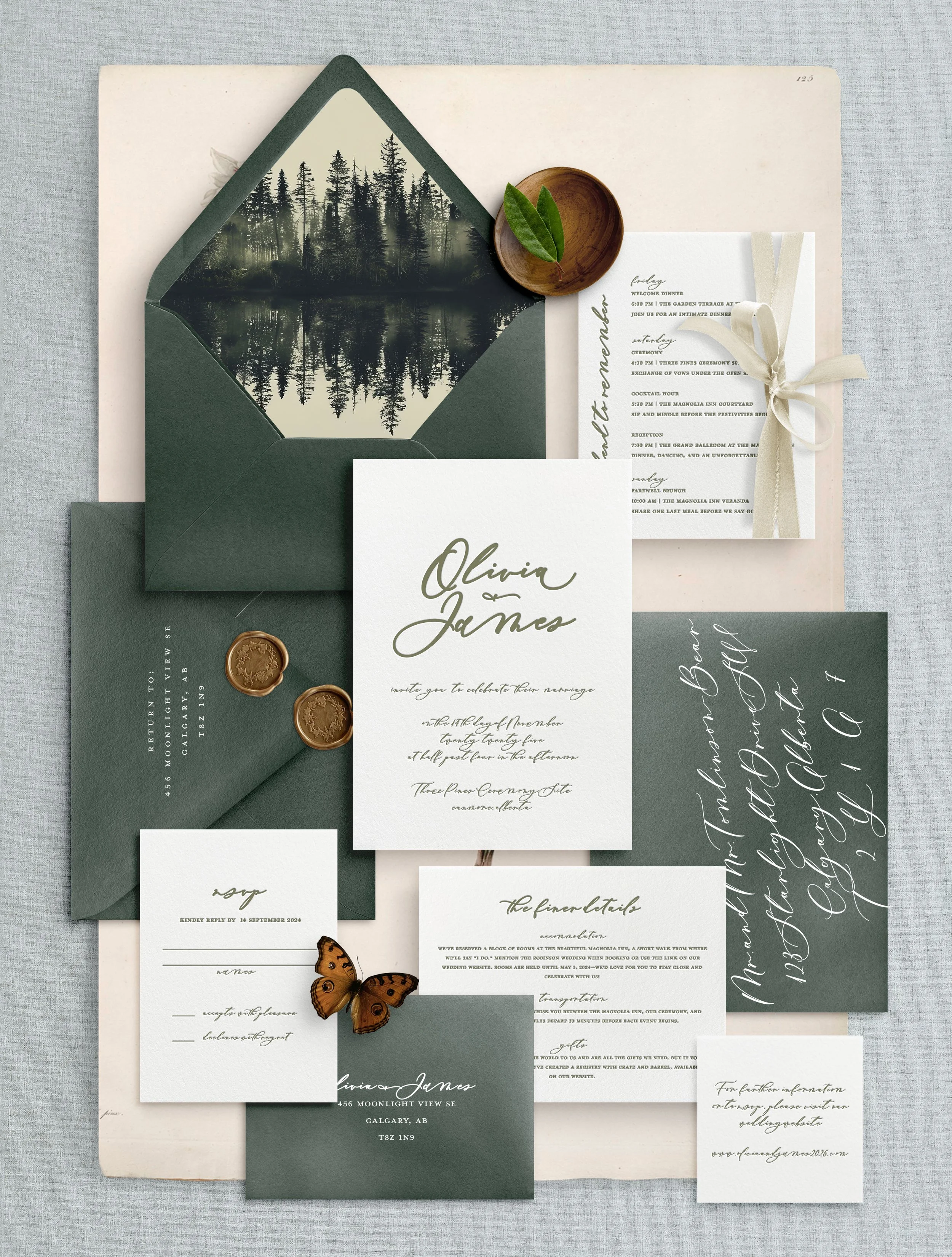 Elegant wedding invitation suite with greenery accents, including a black envelope with a reflective forest image, a white RSVP card, a detailed itinerary, and gold wax seals, arranged on a light gray background.