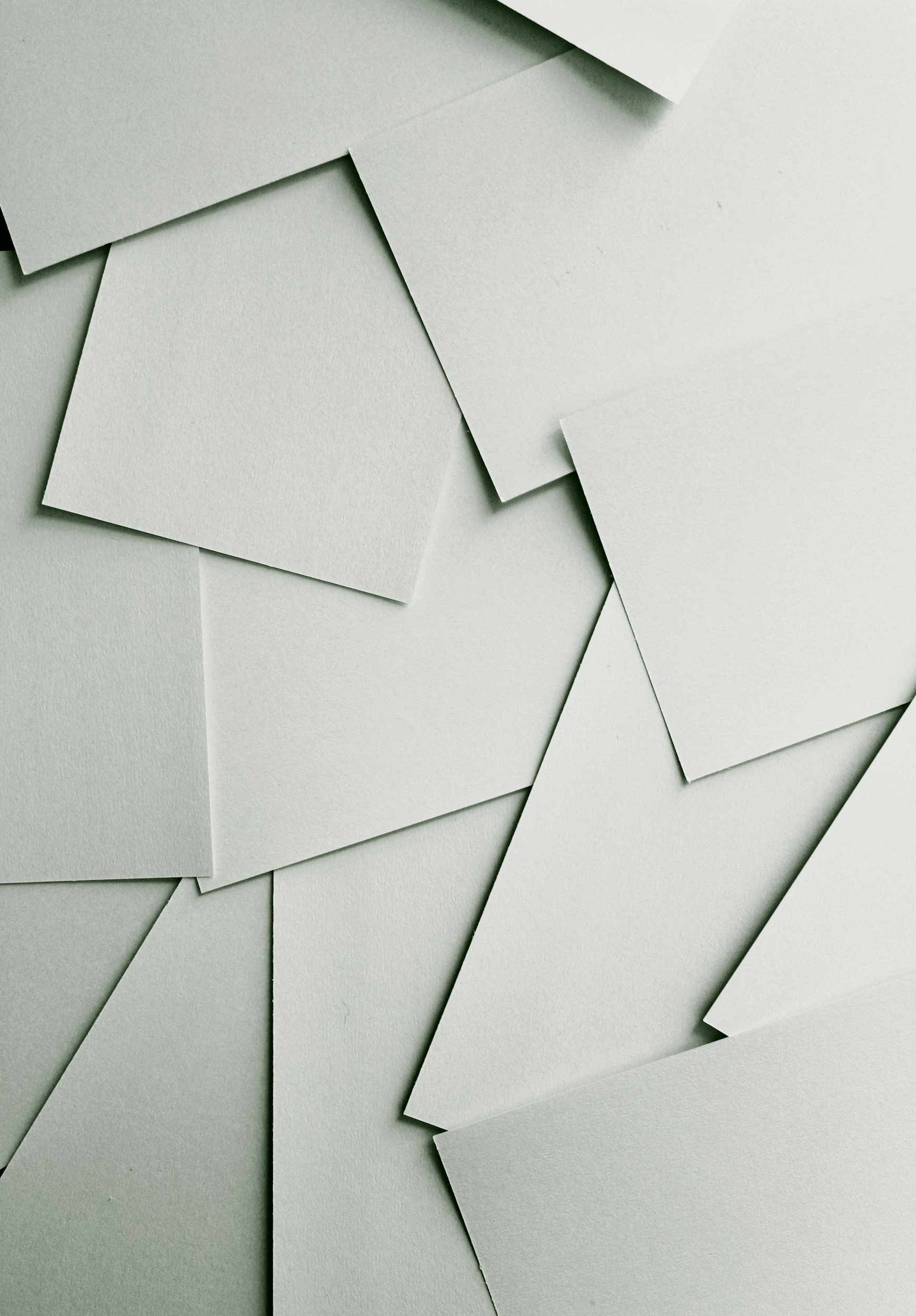 Various blank white paper sheets scattered and overlapping on a flat surface.