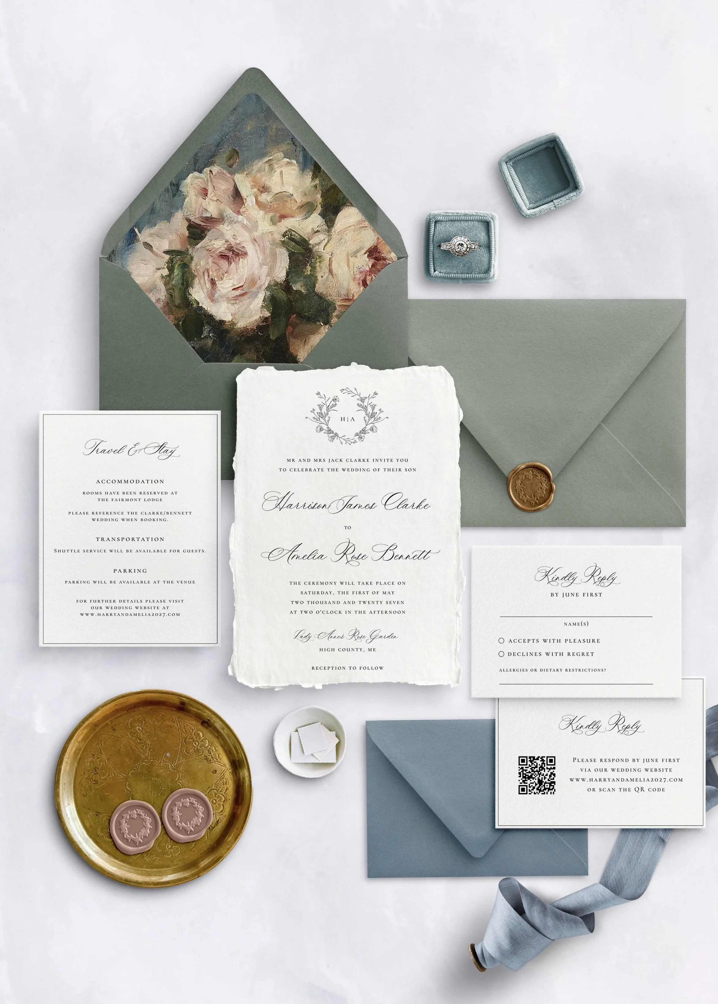 Wedding invitation suite including RSVP card, details card, and main invitation with floral graphics, light blue envelope, gold wax seal with ribbon, small cake candles, and a jewelry box with a ring inside on a white surface.