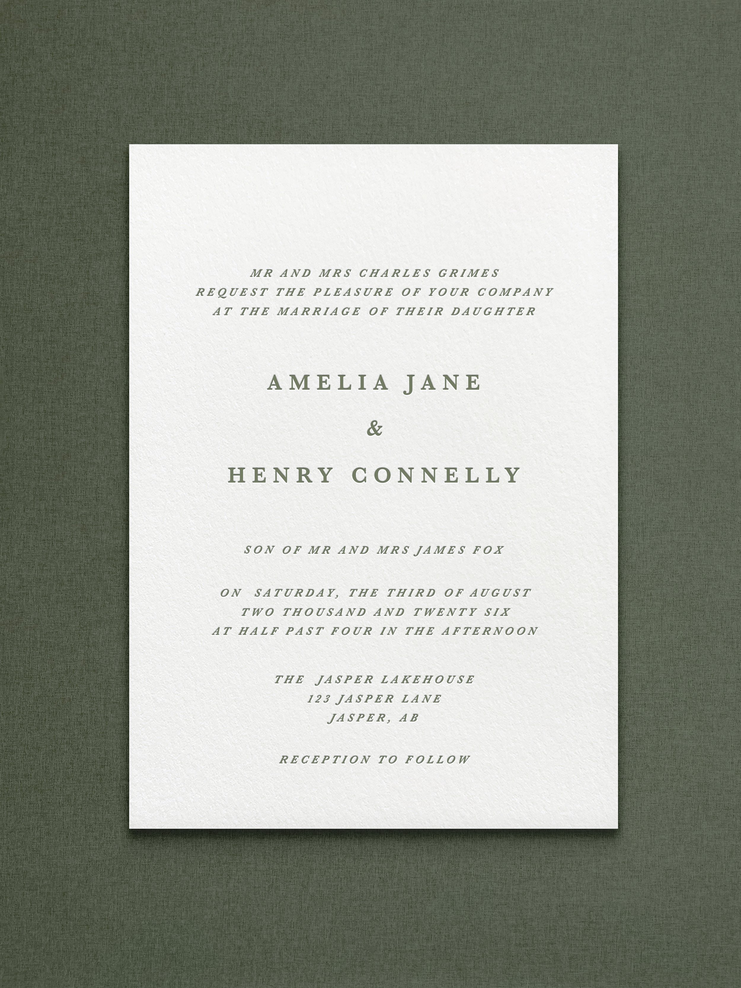 Wedding invitation card with elegant text on a textured white background, centered, on a dark green surface.