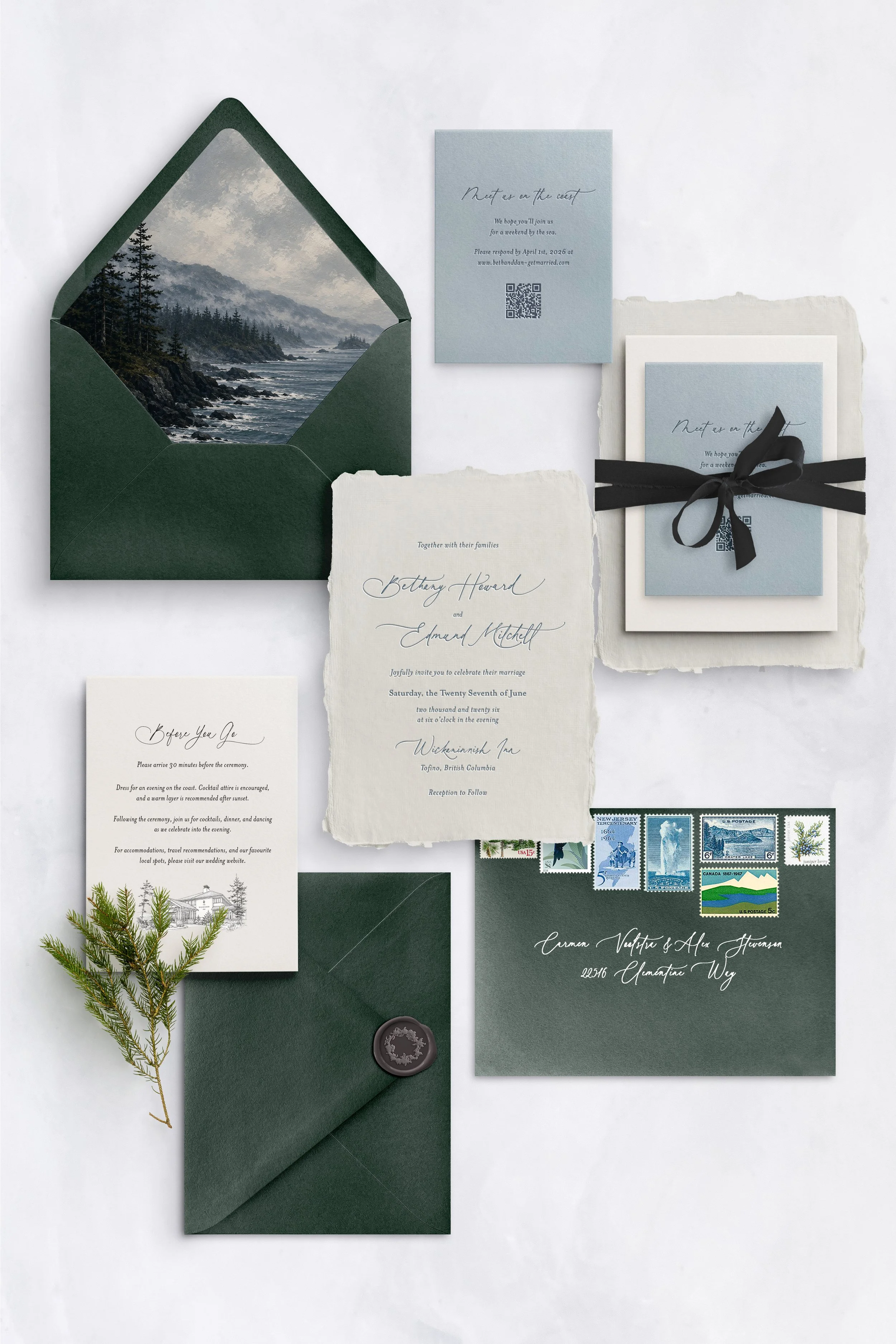Flat lay of wedding invitation suite with forest-themed elements, including a green envelope with a landscape inside, and various RSVP and invitation cards, some tied with black ribbon, along with vintage postage stamps and a sprig of greenery.