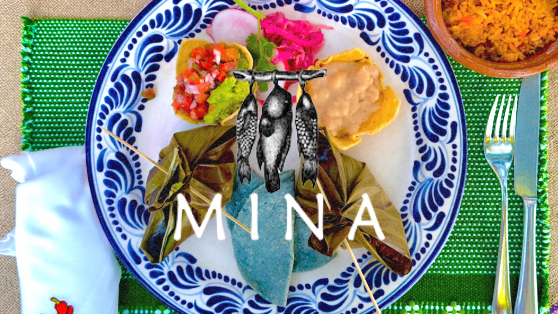 Plate with Mexican food, including a tamale wrapped in leaves, salsa, guacamole, beans, and rice in a separate bowl, decorated with a blue and white pattern, and the word "Mina" on the plate.