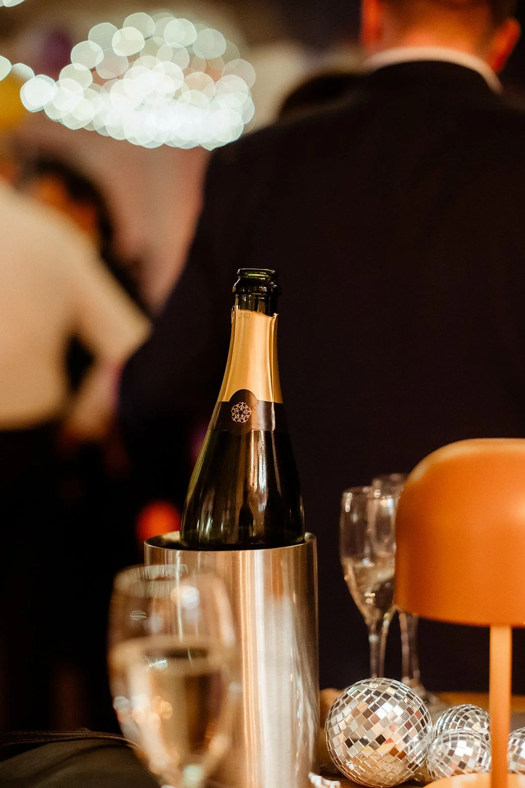 A champagne bottle in an ice bucket on a table at a celebration or party.