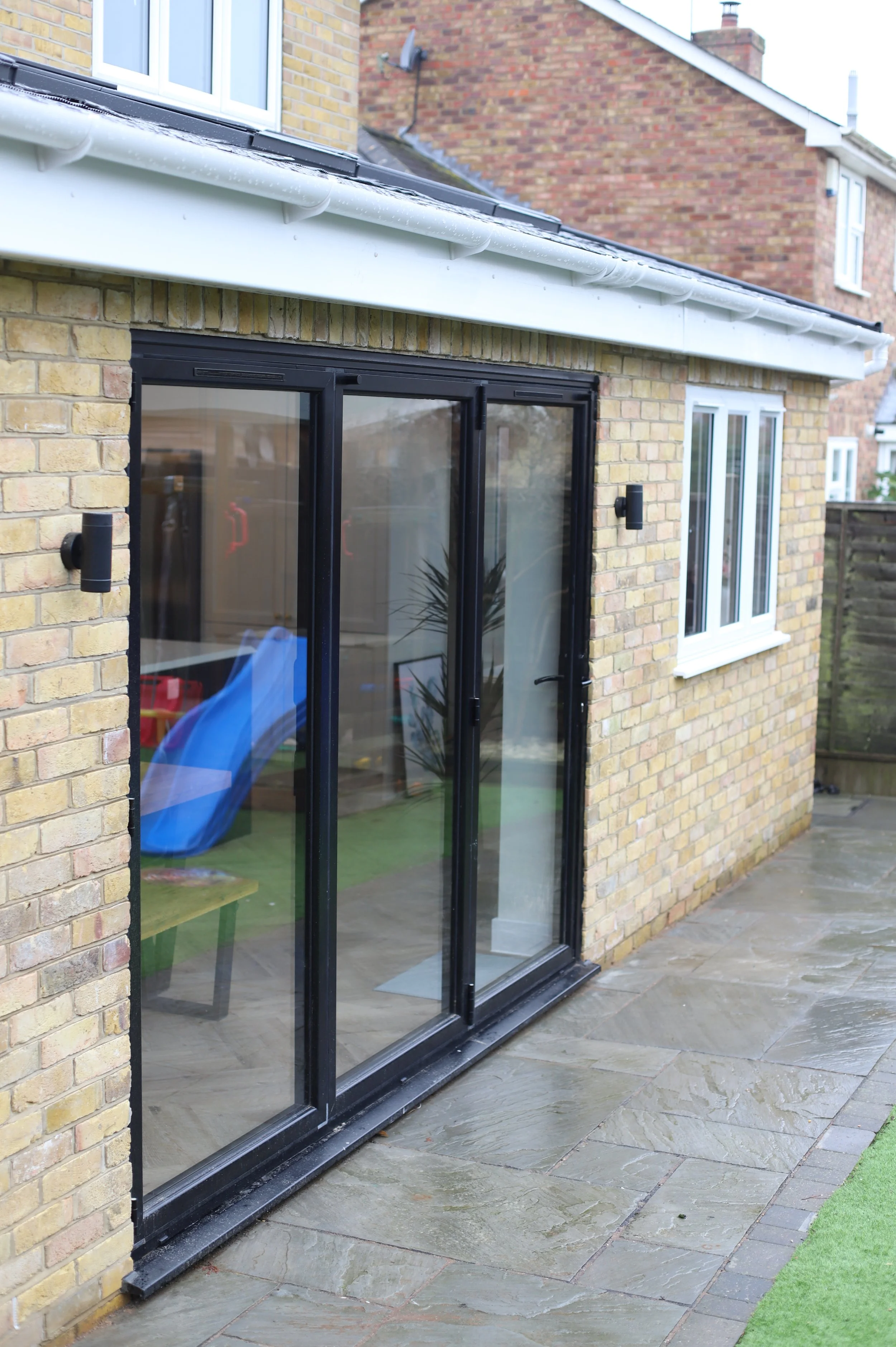 Rear extension with black bi-folding doors and natural stone patio.