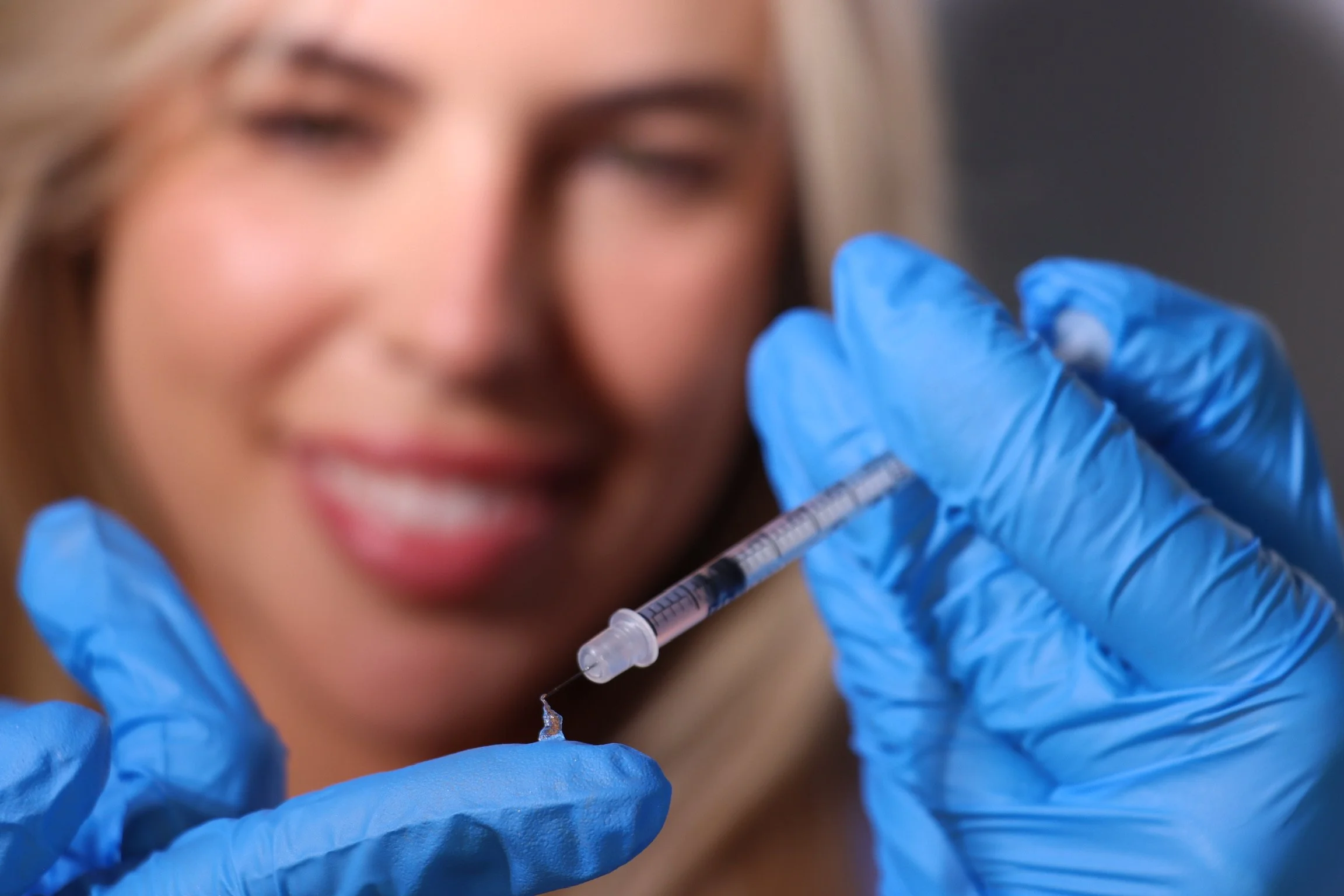 Close-up of a person with blue gloves holding a syringe.