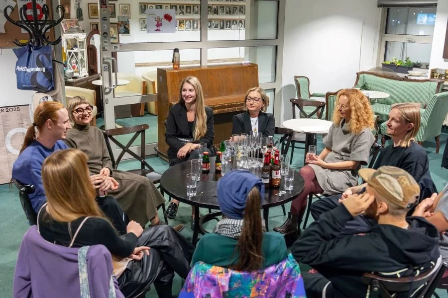 Group of people sit around a round table deep in discussion