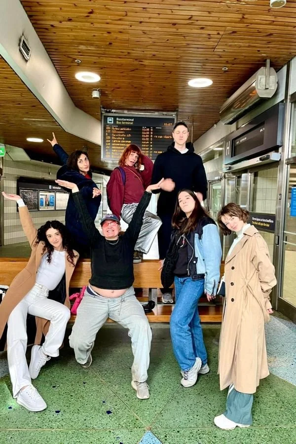 Group of artists pose for a group photo with arms up and showing great enjoyment and energy
