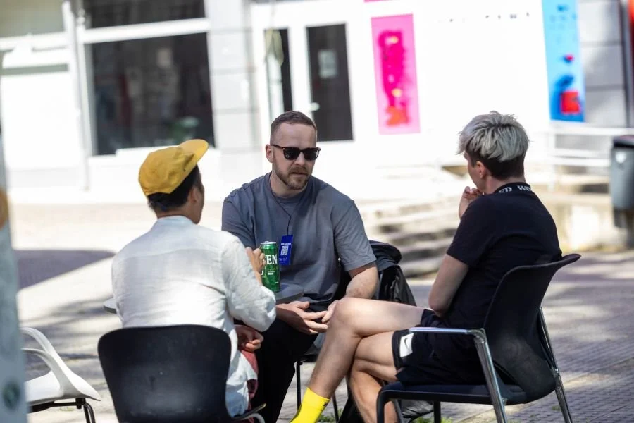 Three people sit outside on a sunny day chatting