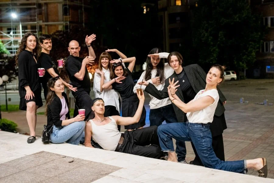 Visiting Artists on a night out pose together lifting their ar,s in dramatic dance poses