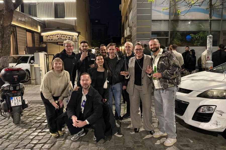 Group photo of the Visiting Artist Programme participants outside in a city setting in the evening