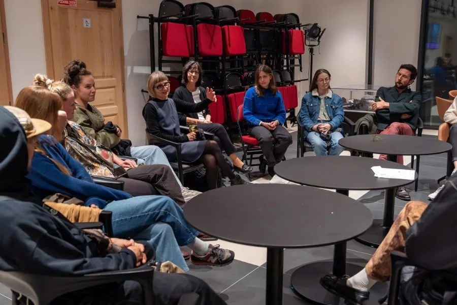 Group sit around round tables in conversation at a festival discussion group
