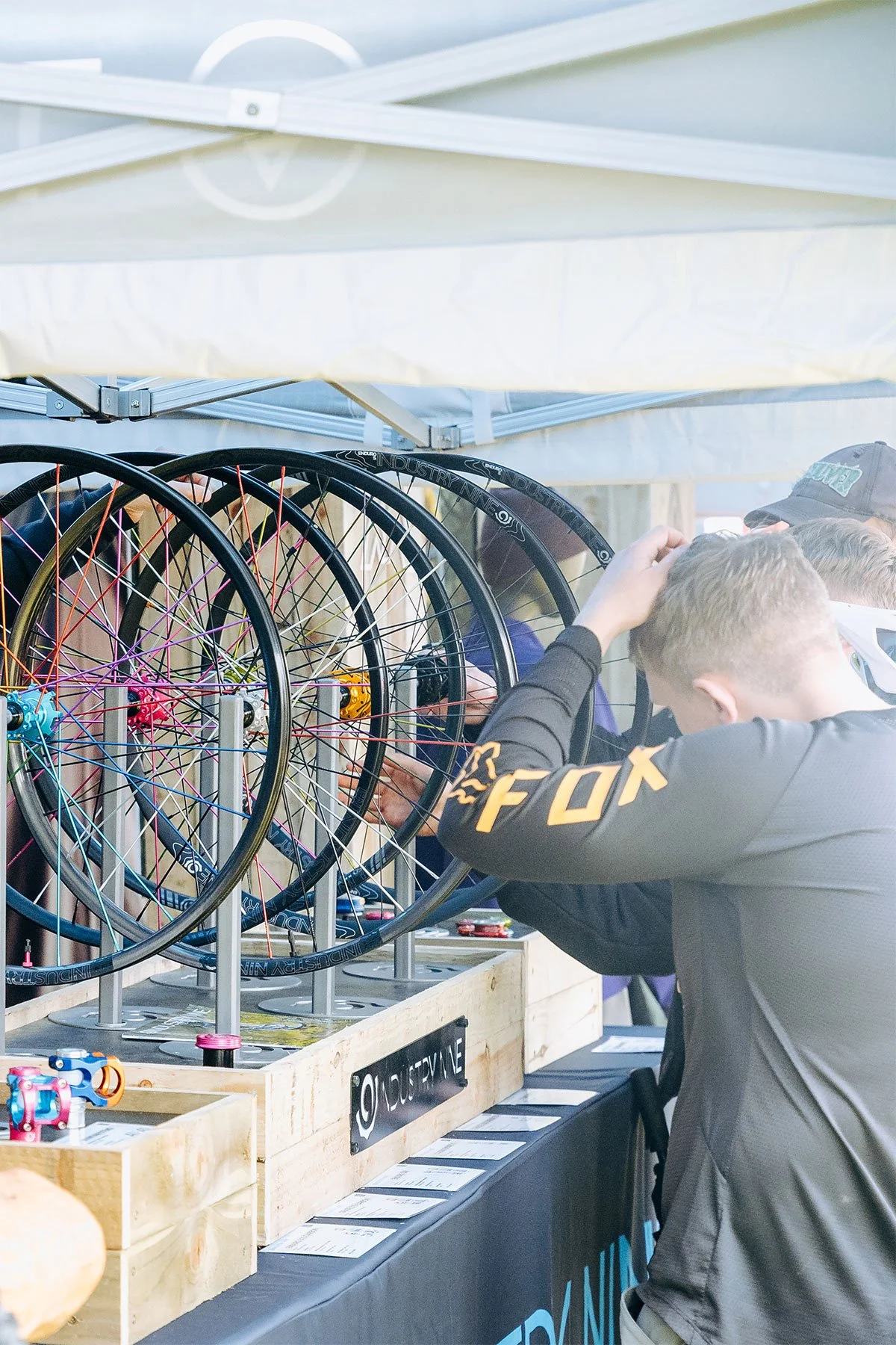 People examining and selecting bicycle wheels at an outdoor booth.