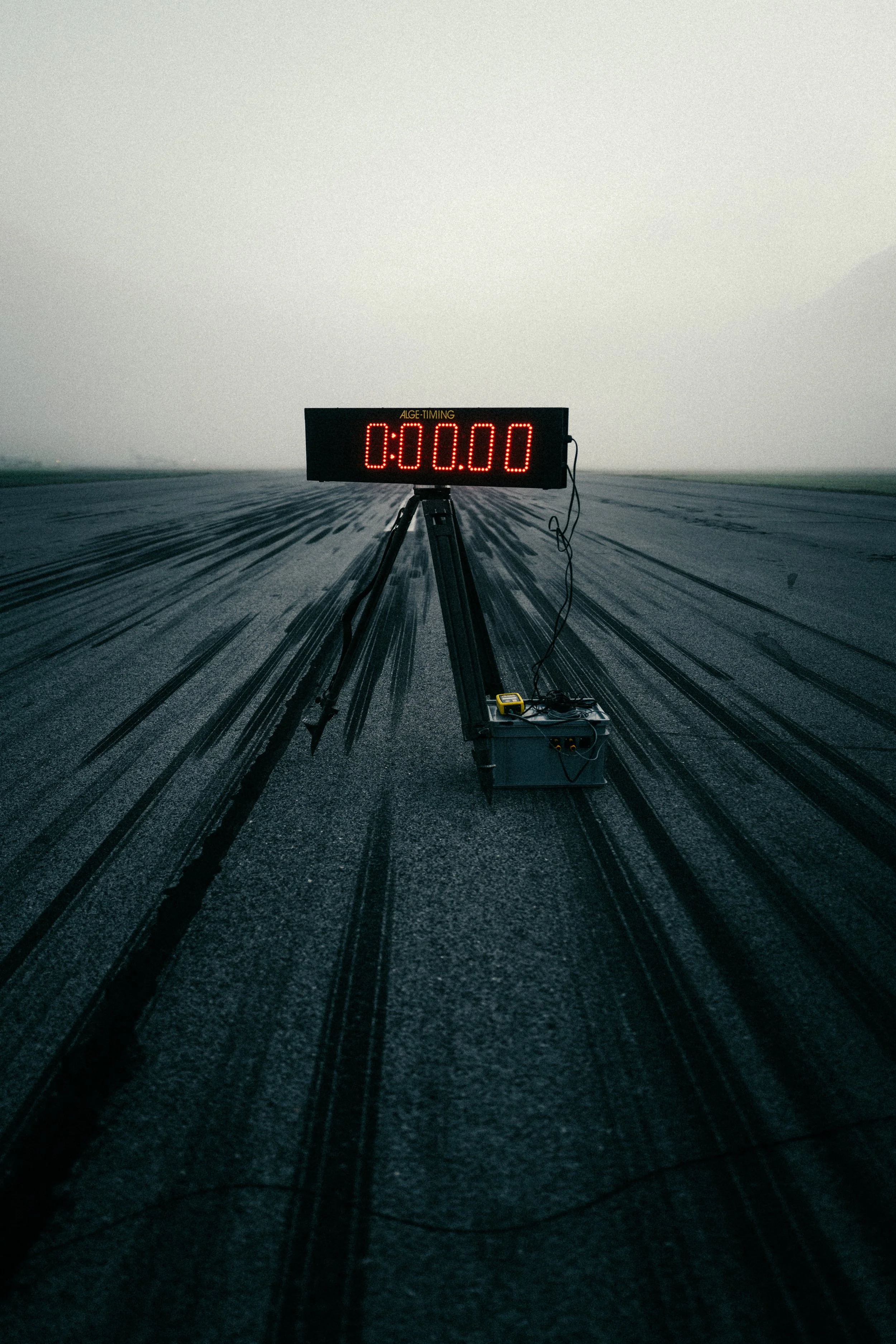 Eine Zeittafel auf einer Rennbahn mit einer schwarzen Anzeige, die auf 00:00 steht, im Nebel. Die Bahn hat schwarze Spuren auf der Oberfläche.