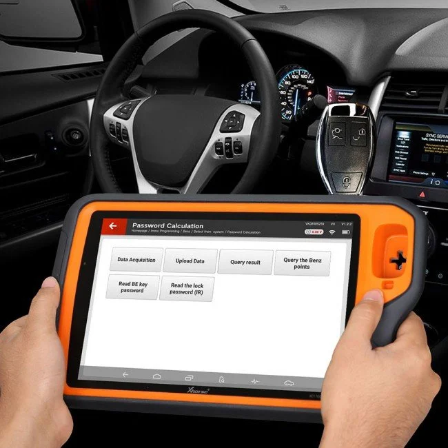 Person holding an orange diagnostic tablet inside a car, displaying a password calculation interface.