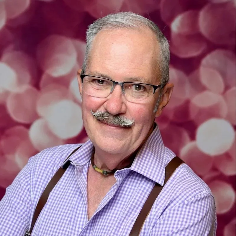 Smiling man speaking or singing into a microphone on stage.