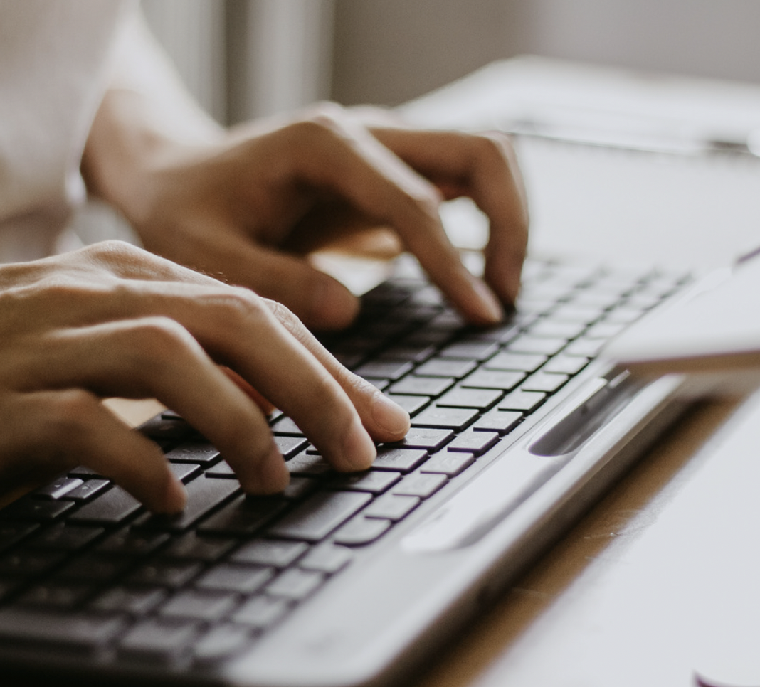 Close-up of hands typing on a laptop keyboard.