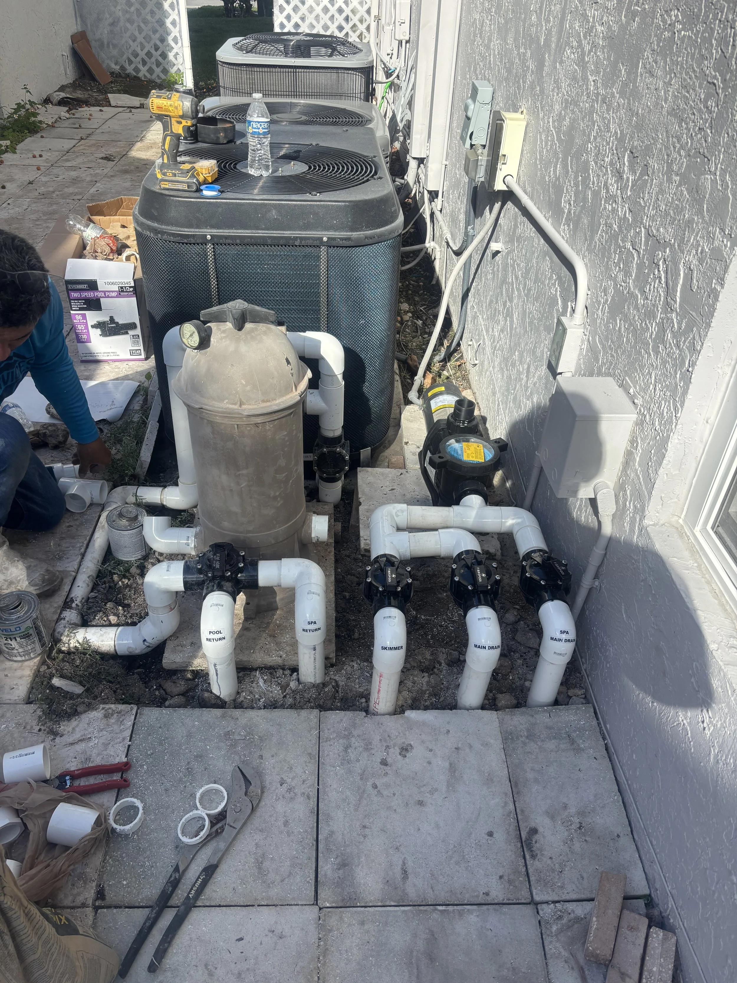 A series of white PVC pipes with blue jandy and black jandy valves connected to new pool pump