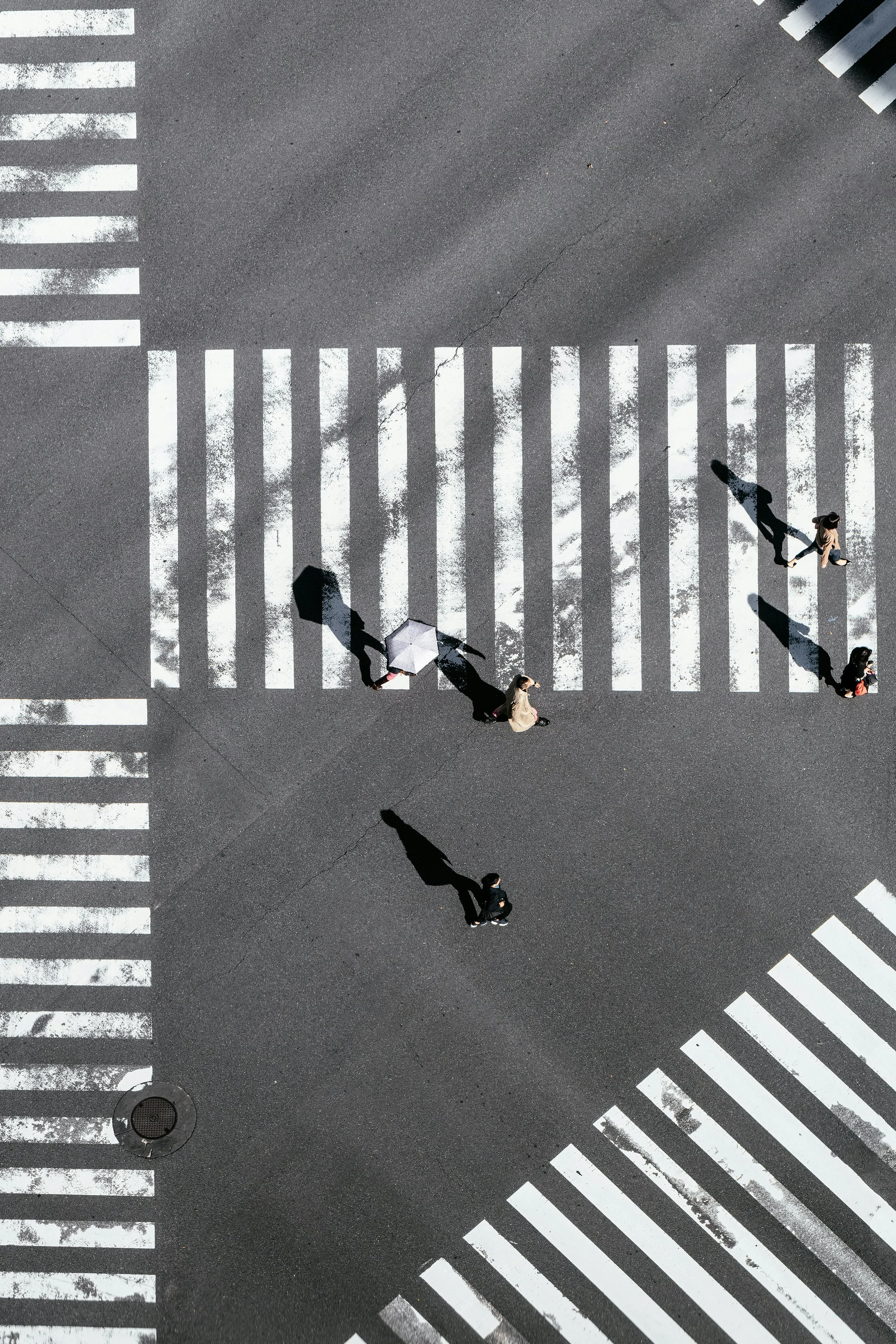 Vue aérienne de personnes traversant un passage piéton marqué par des bandes blanches.