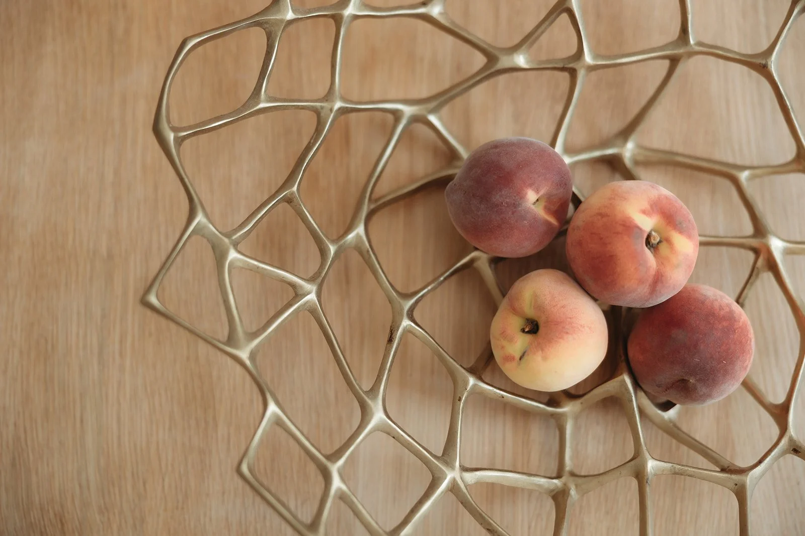 Decorative bowl of peaches on a wooden surface