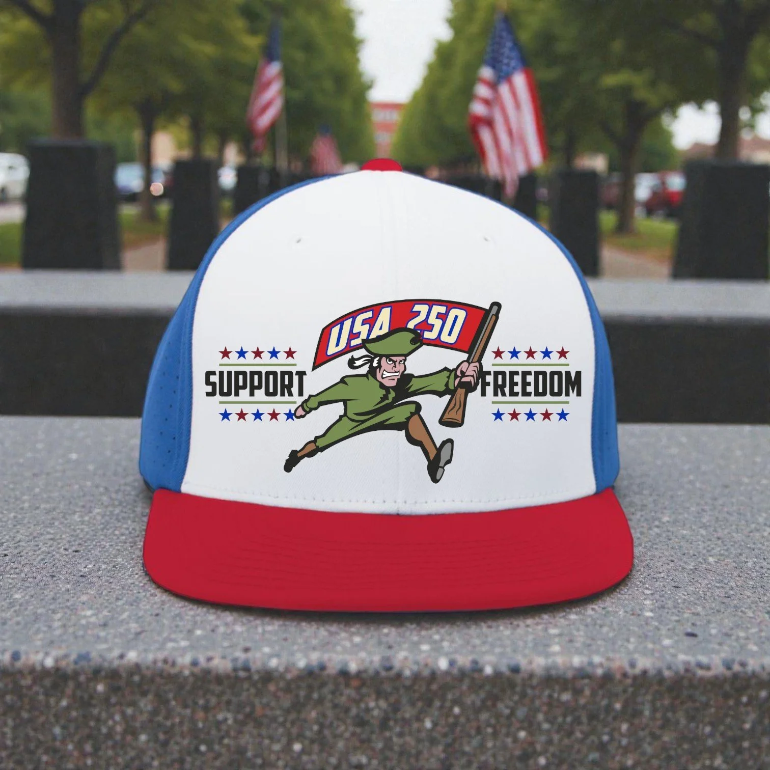 A patriotic baseball cap with red, white, and blue colors. The front features a cartoon revolutionary with a musket, and text reading 'USA 250 Support Freedom'. American flags are in the background.