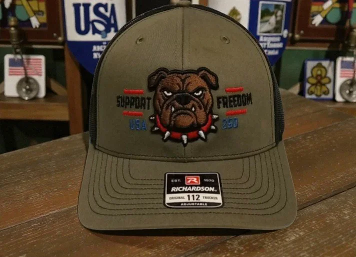 A khaki-colored Richardson trucker cap with an embroidered image of a bulldog wearing a spiked collar. The cap also has the words "Support" and "Freedom" on either side of the bulldog, along with "USA" and "250".