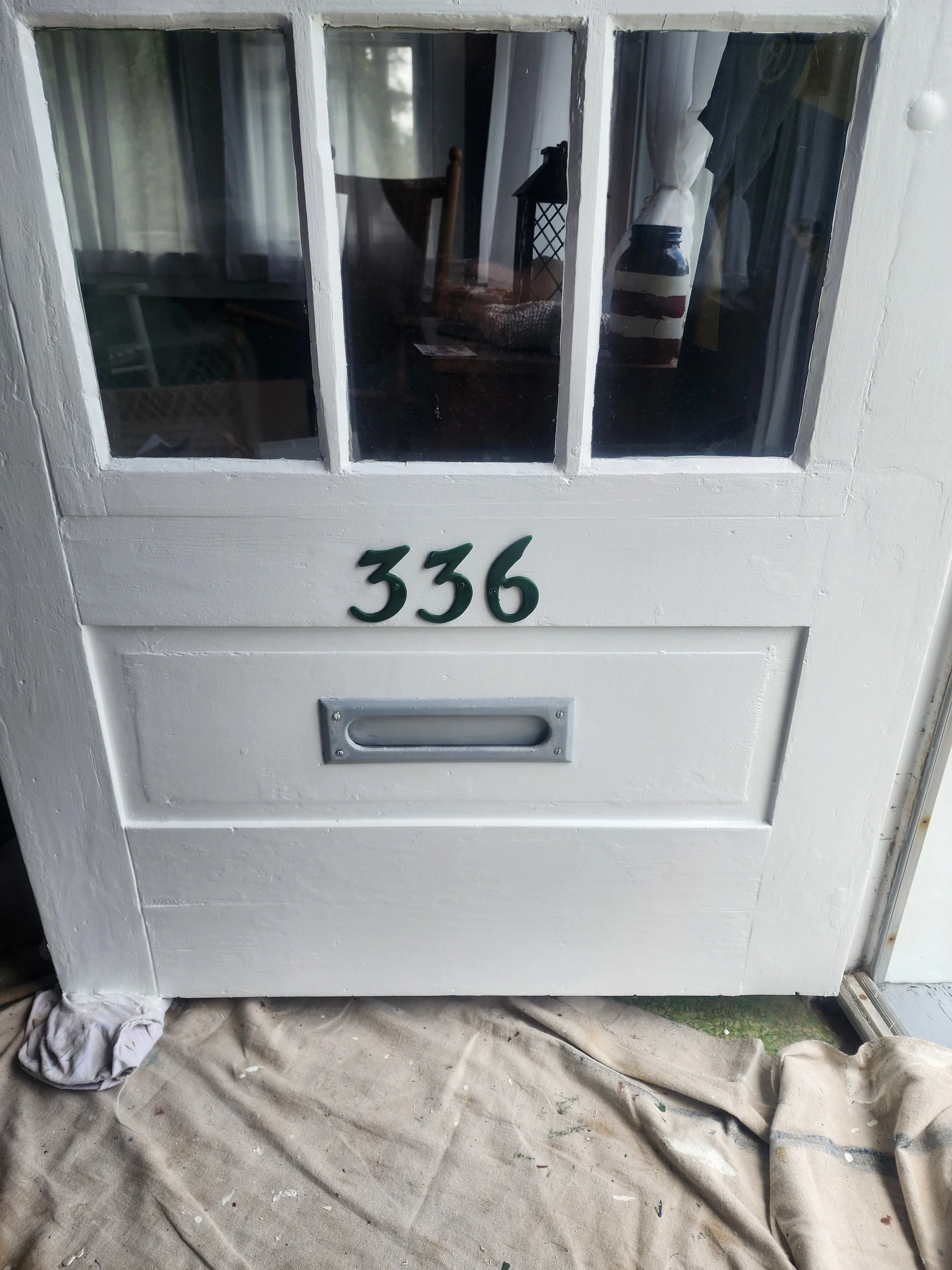 A white front door with a glass window divided into four panes, displaying house number 336 in black numbers and a silver mailbox slot below.