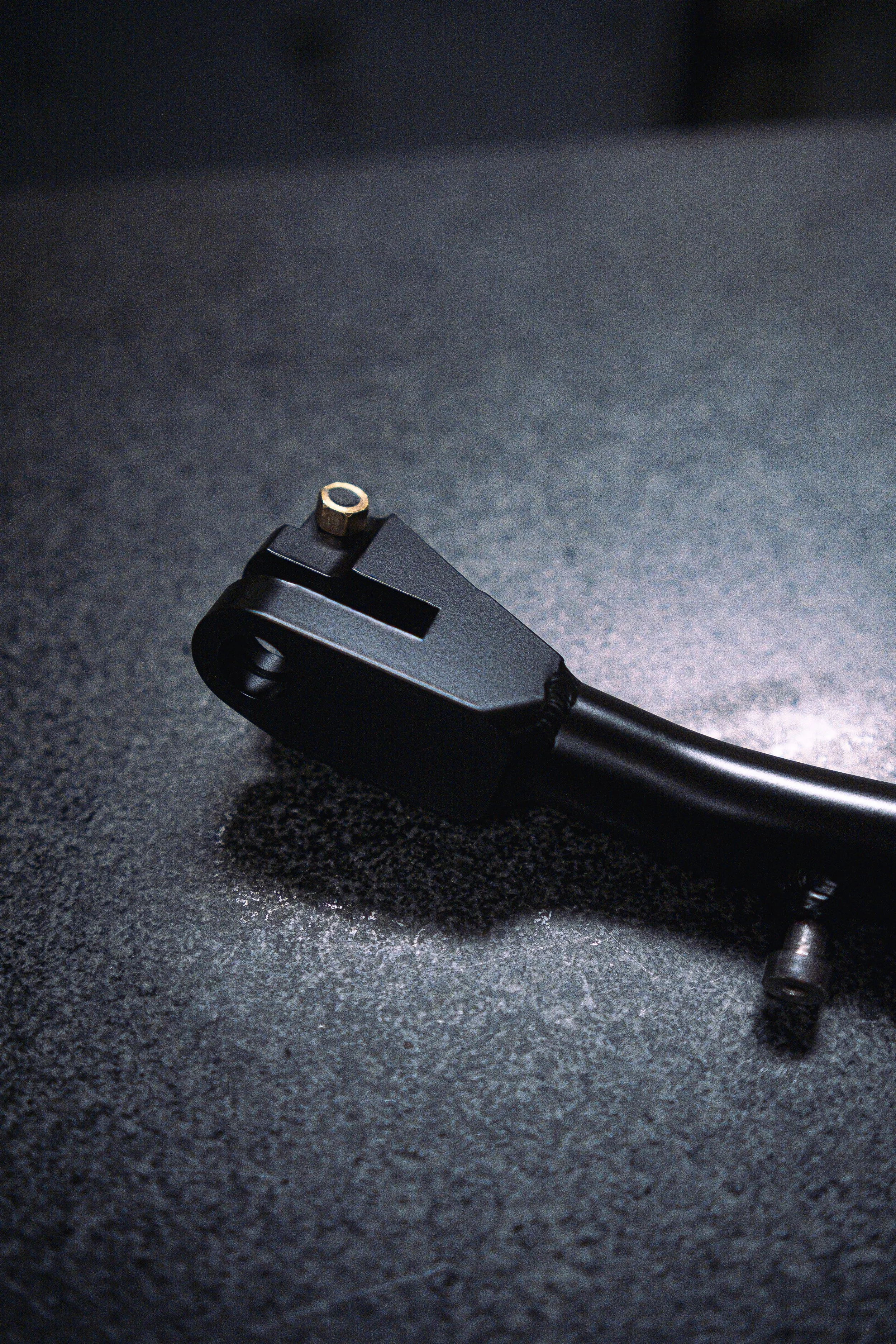 A metal industrial tool part with black and gold-colored components, resting on a scratched, metallic surface.