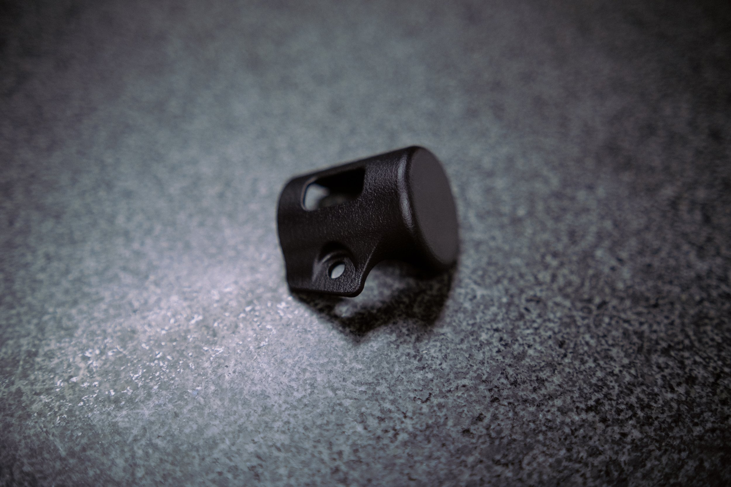 A small black plastic bracket on a gray textured surface.
